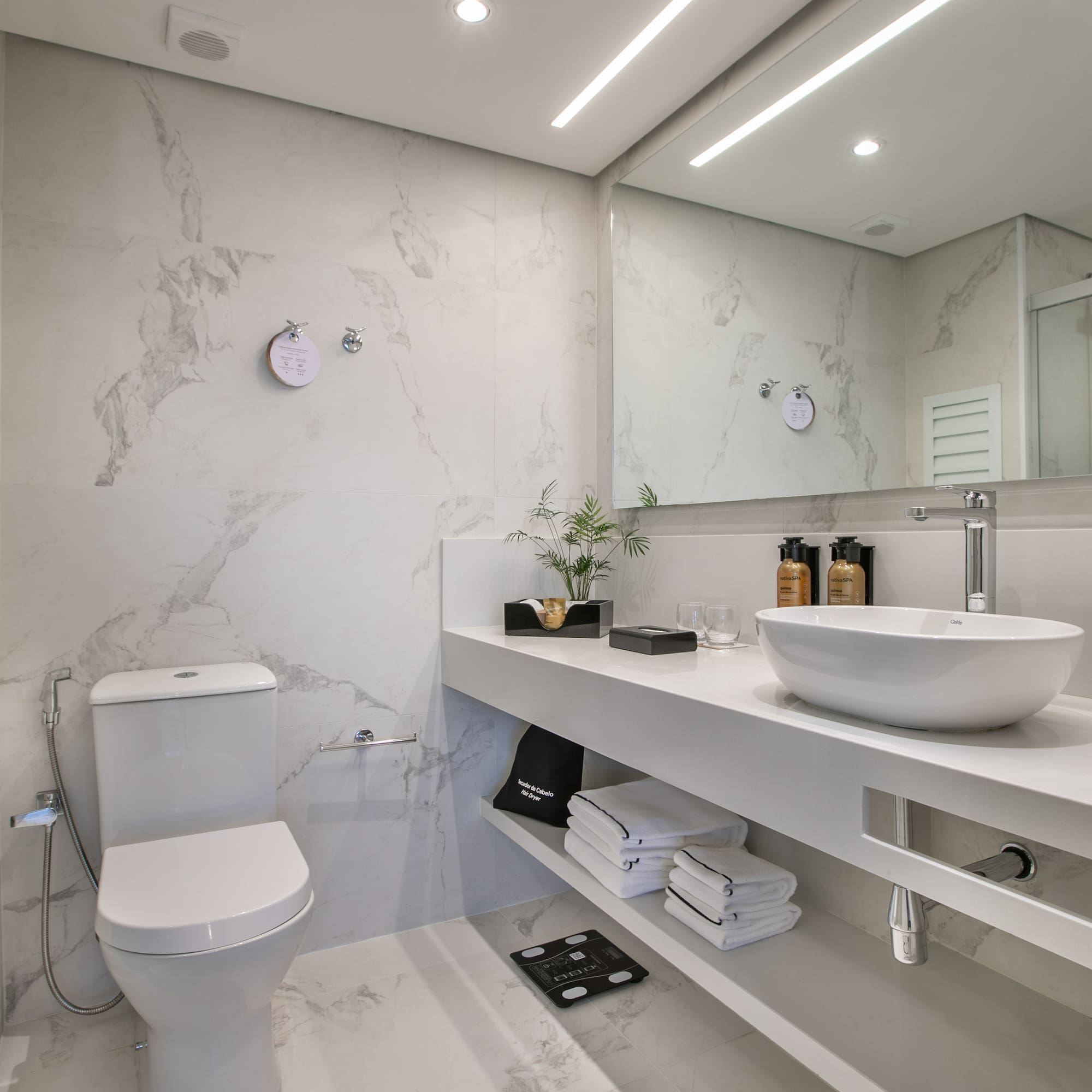 Modern white marble bathroom with sleek vanity, vessel sink, and toilet.