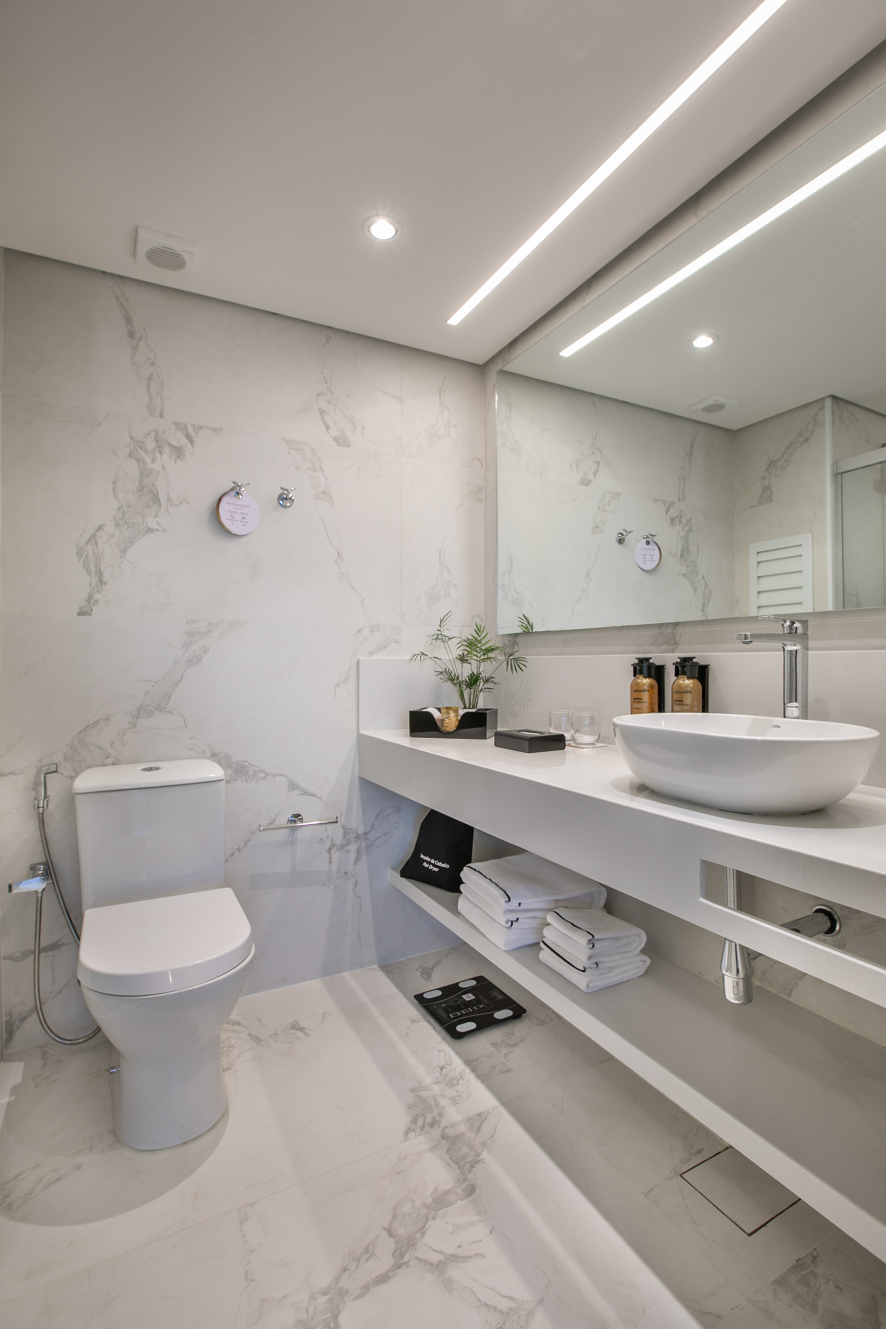 Modern white marble bathroom with sleek vanity, vessel sink, and toilet.