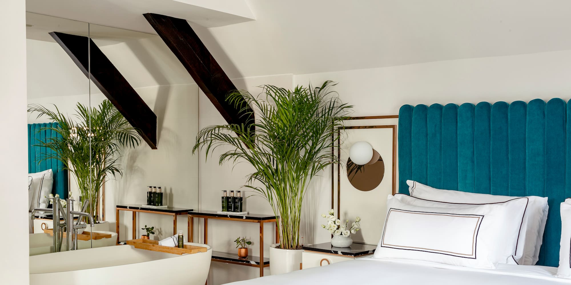 a room with a bed and bathtub and plants