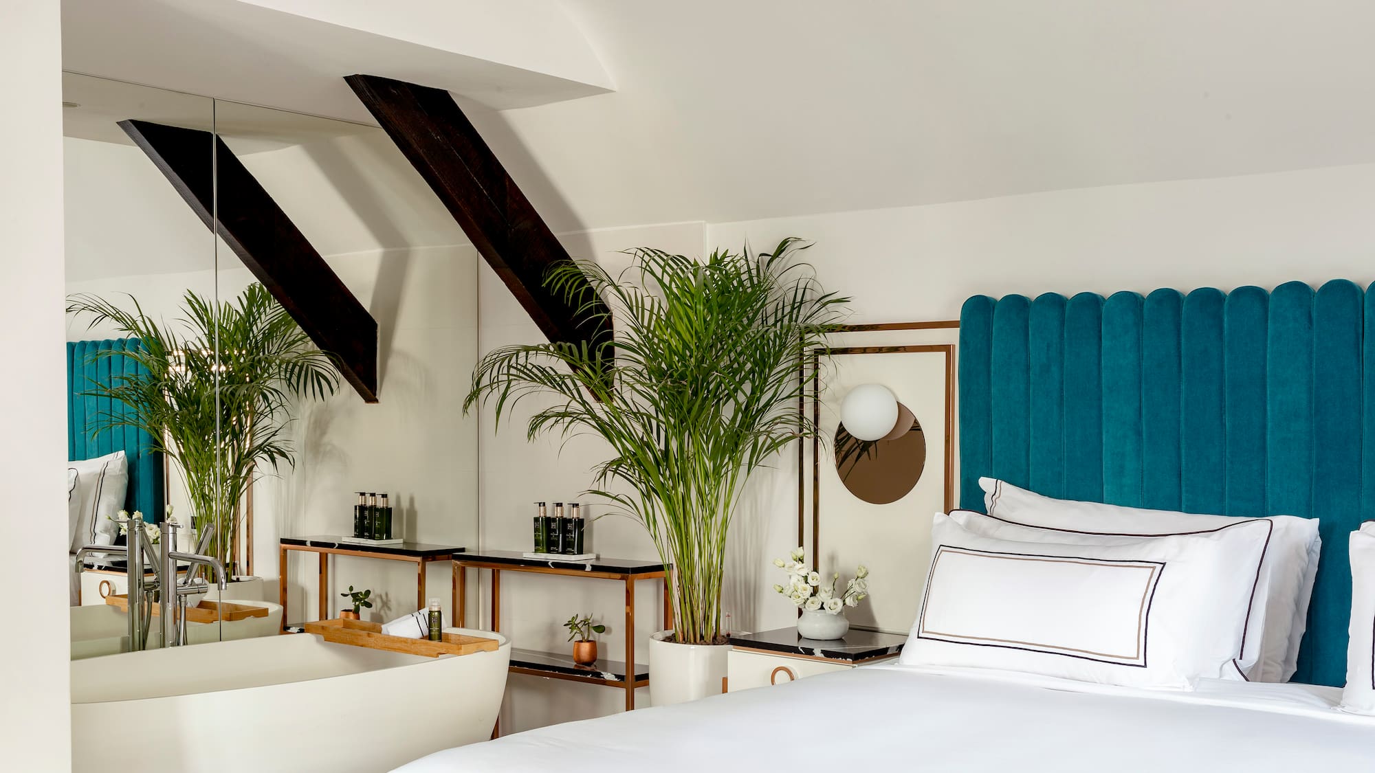 a room with a bed and bathtub and plants