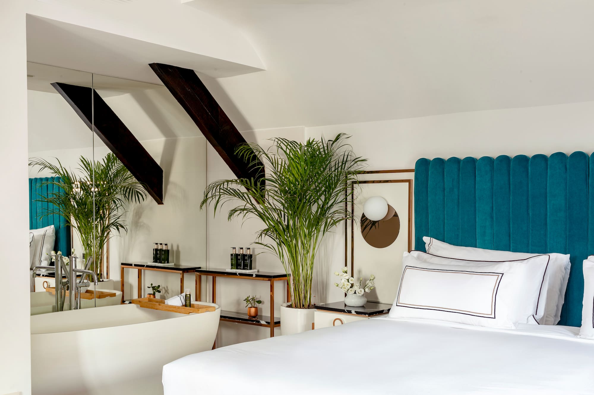 a room with a bed and bathtub and plants