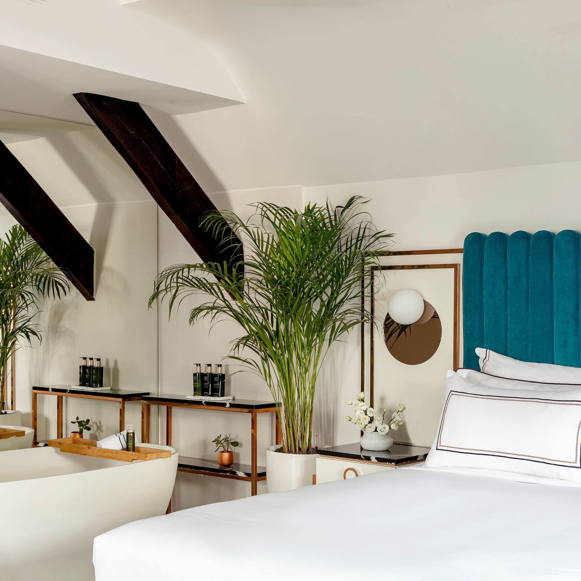 a room with a bed and bathtub and plants