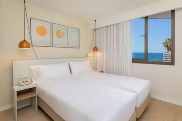 a bed with white sheets and pillows in a room with a window