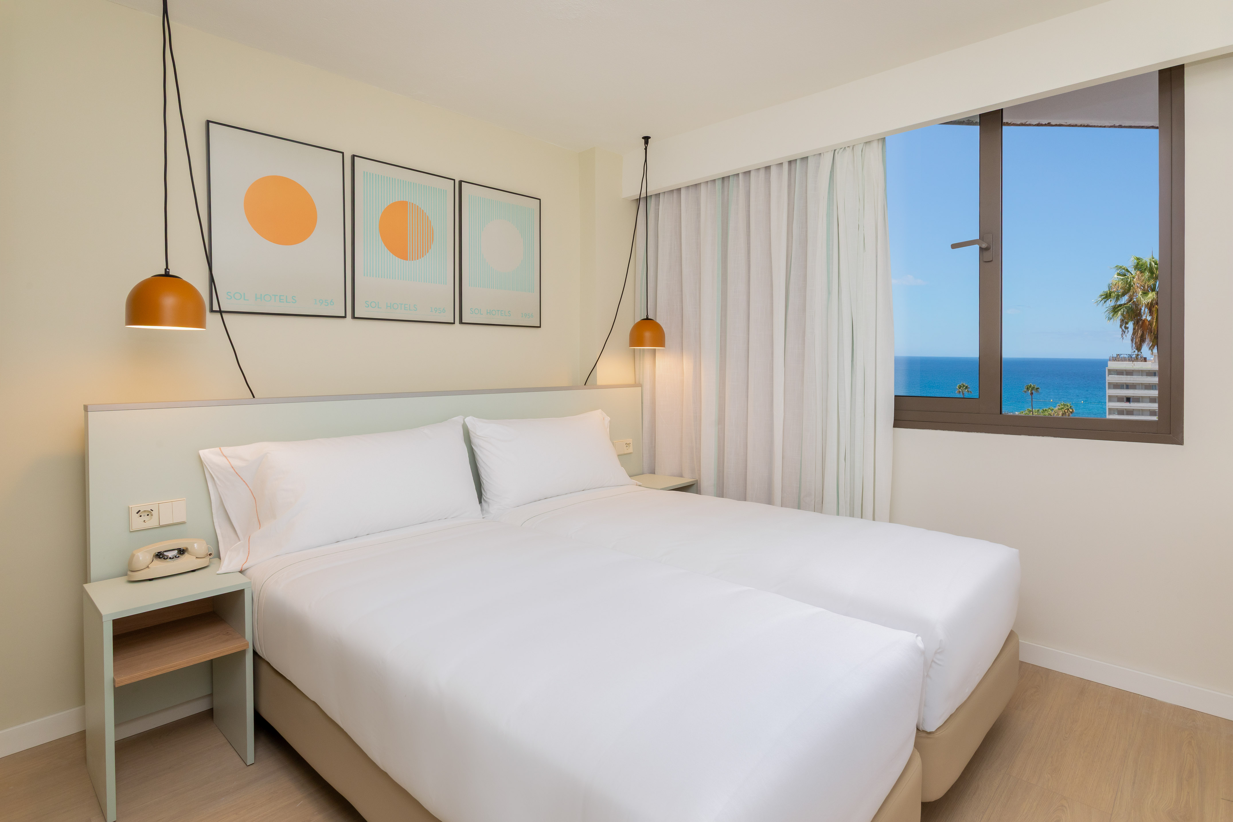 Sol Hotels bedroom with ocean view, twin beds, modern design, and wall art.
