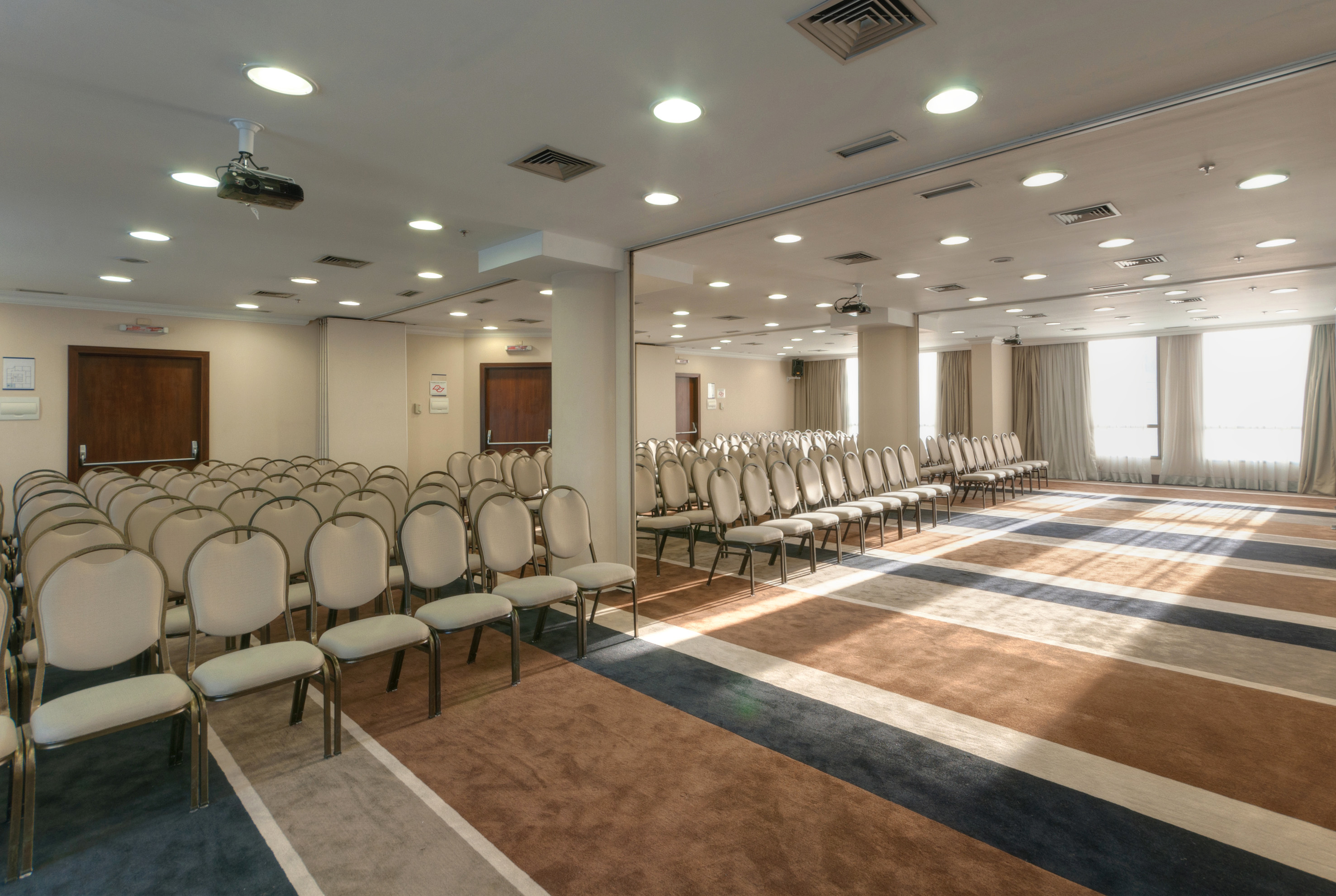 Conference room with empty chairs, ceiling projector, and striped carpet.