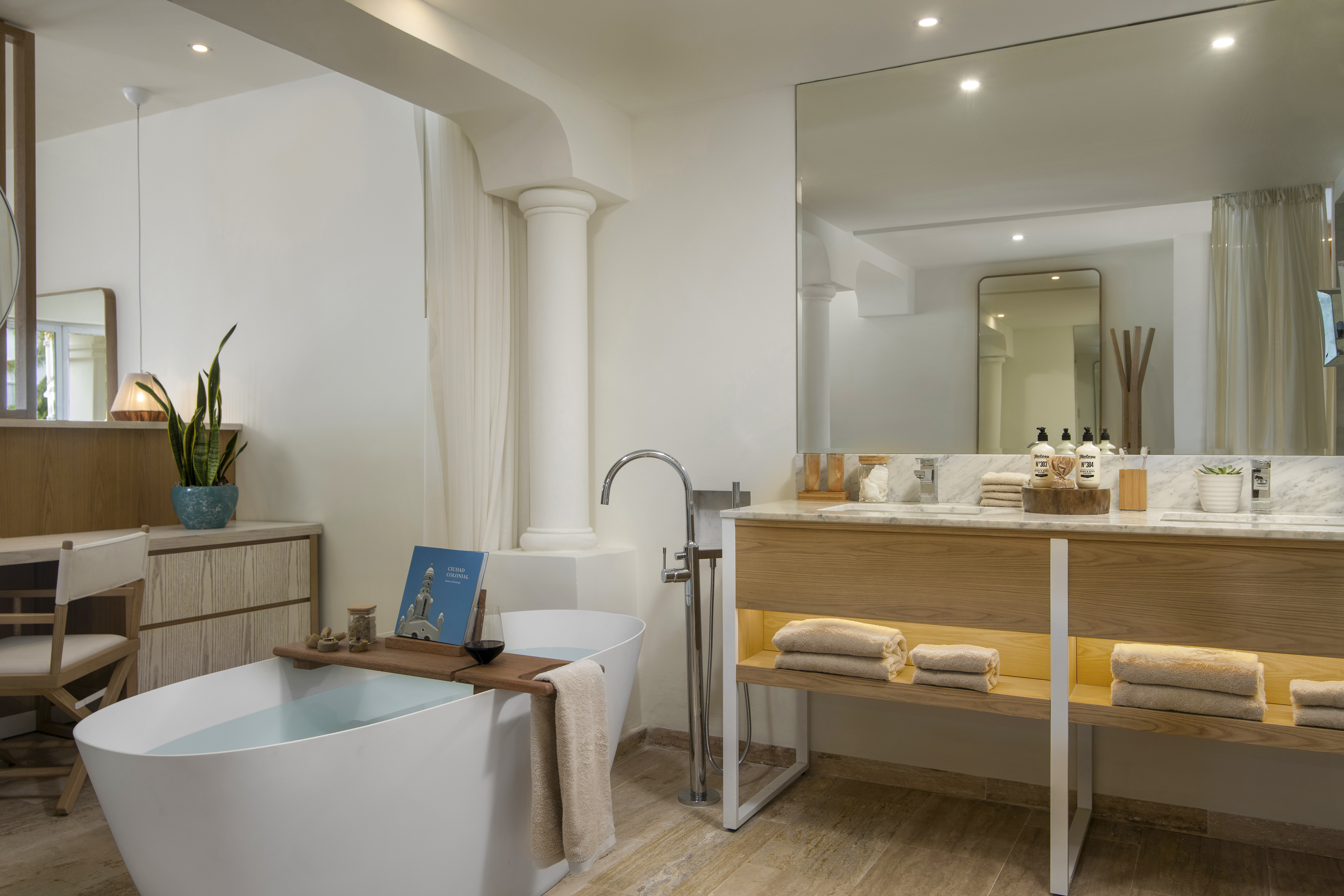 Luxury hotel bathroom with freestanding tub, wood vanity, marble, and mirror.
