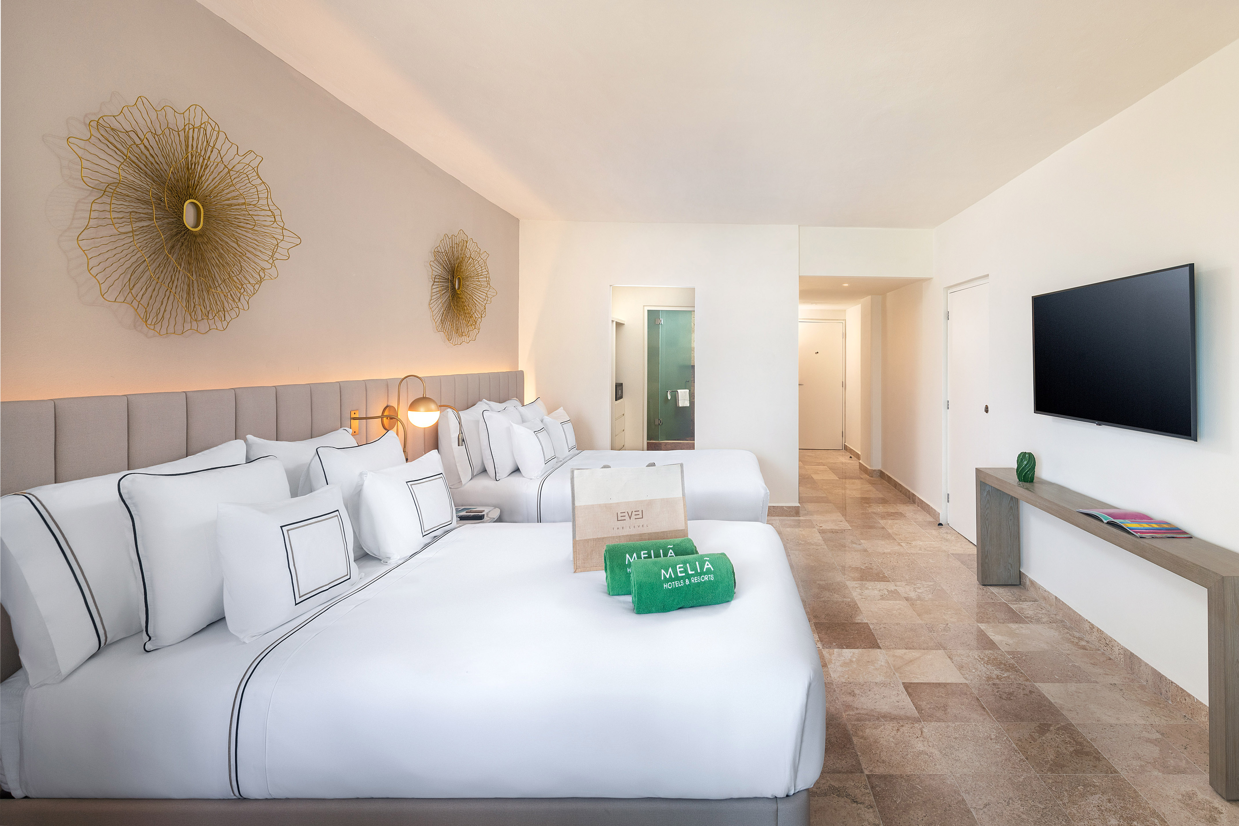 Spacious Melia hotel room with two queen beds, modern decor, and tiled floor.