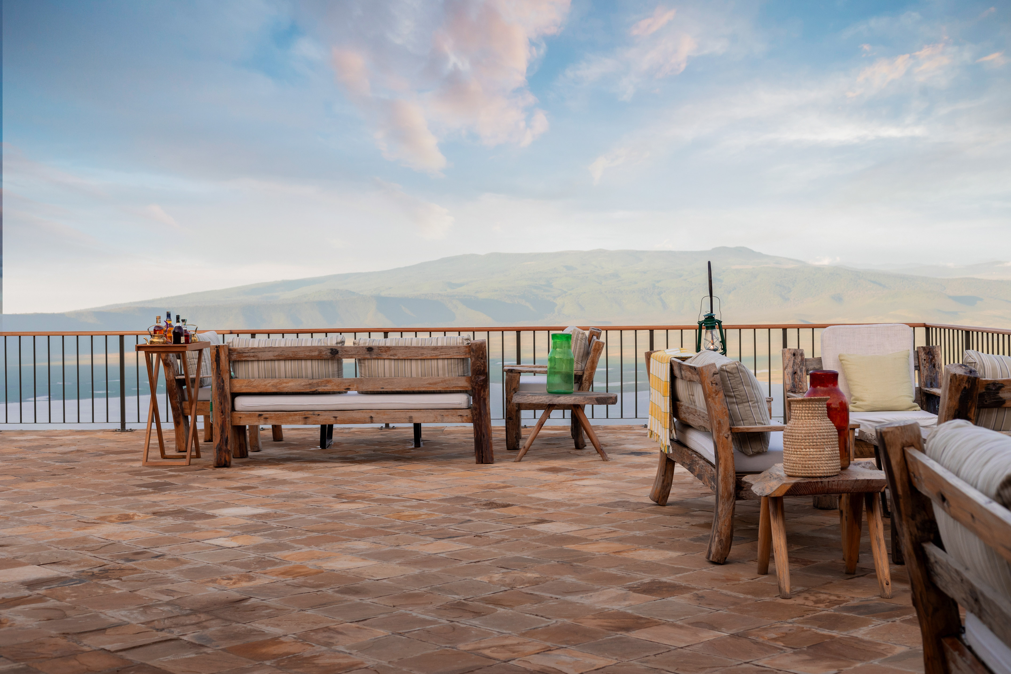 Terrace with rustic wooden seating, panoramic mountain views, Ngorongoro Crater.
