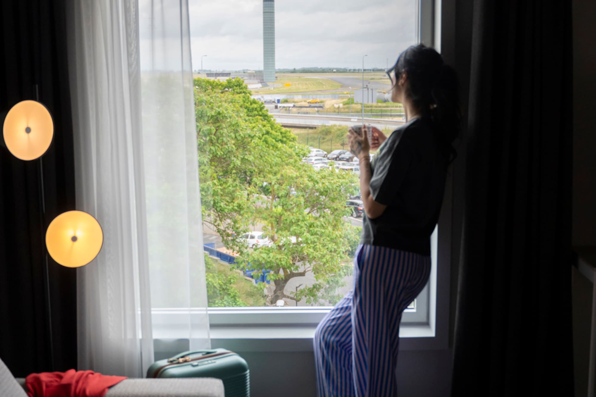 a woman standing in front of a window looking out a window