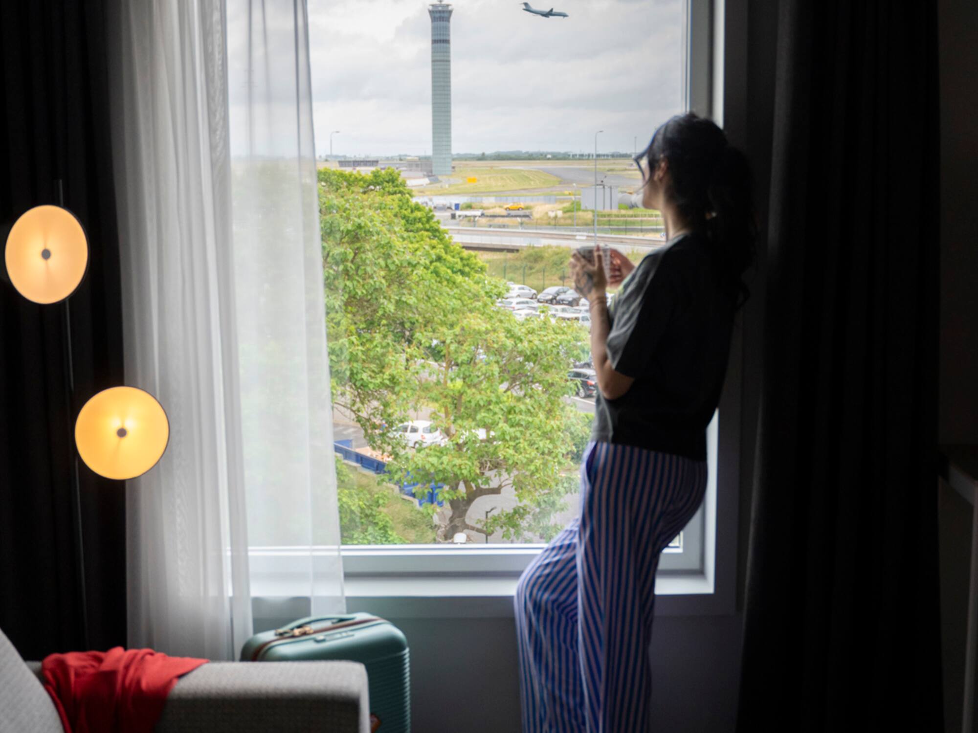 a woman standing in front of a window looking out a window