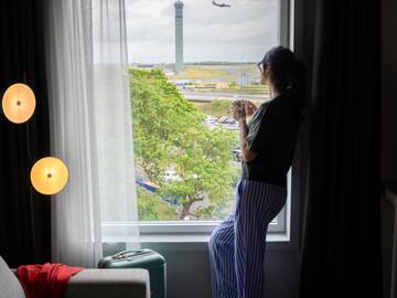 a woman standing in front of a window looking out a window