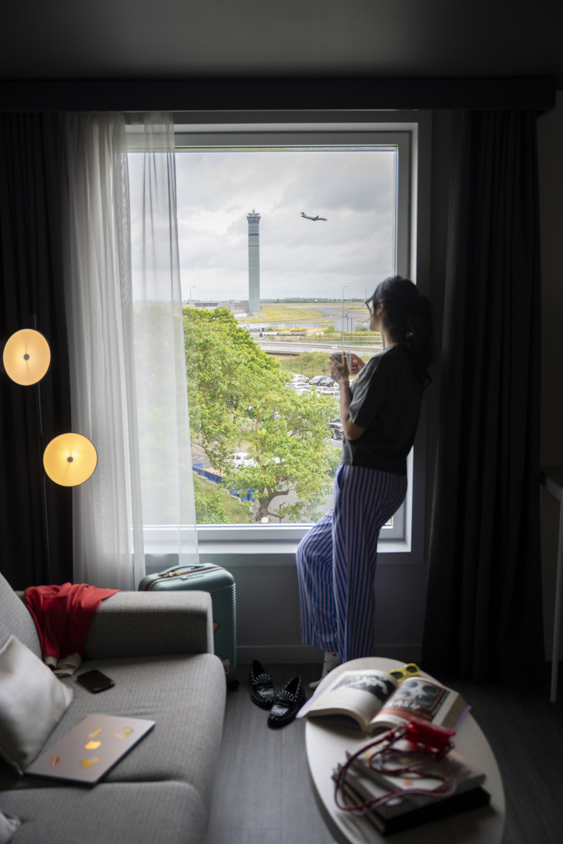 Traveler watching plane take off from modern airport hotel room.