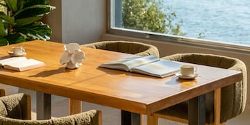a table with a book and two chairs by a window