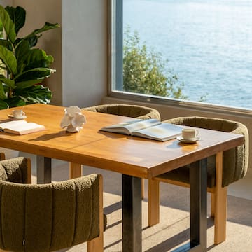 a table with a book and two chairs by a window