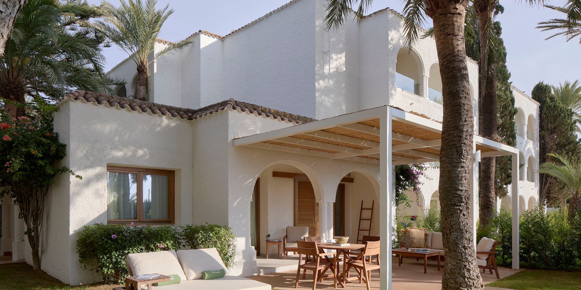 a patio area with chairs and tables in front of a white building