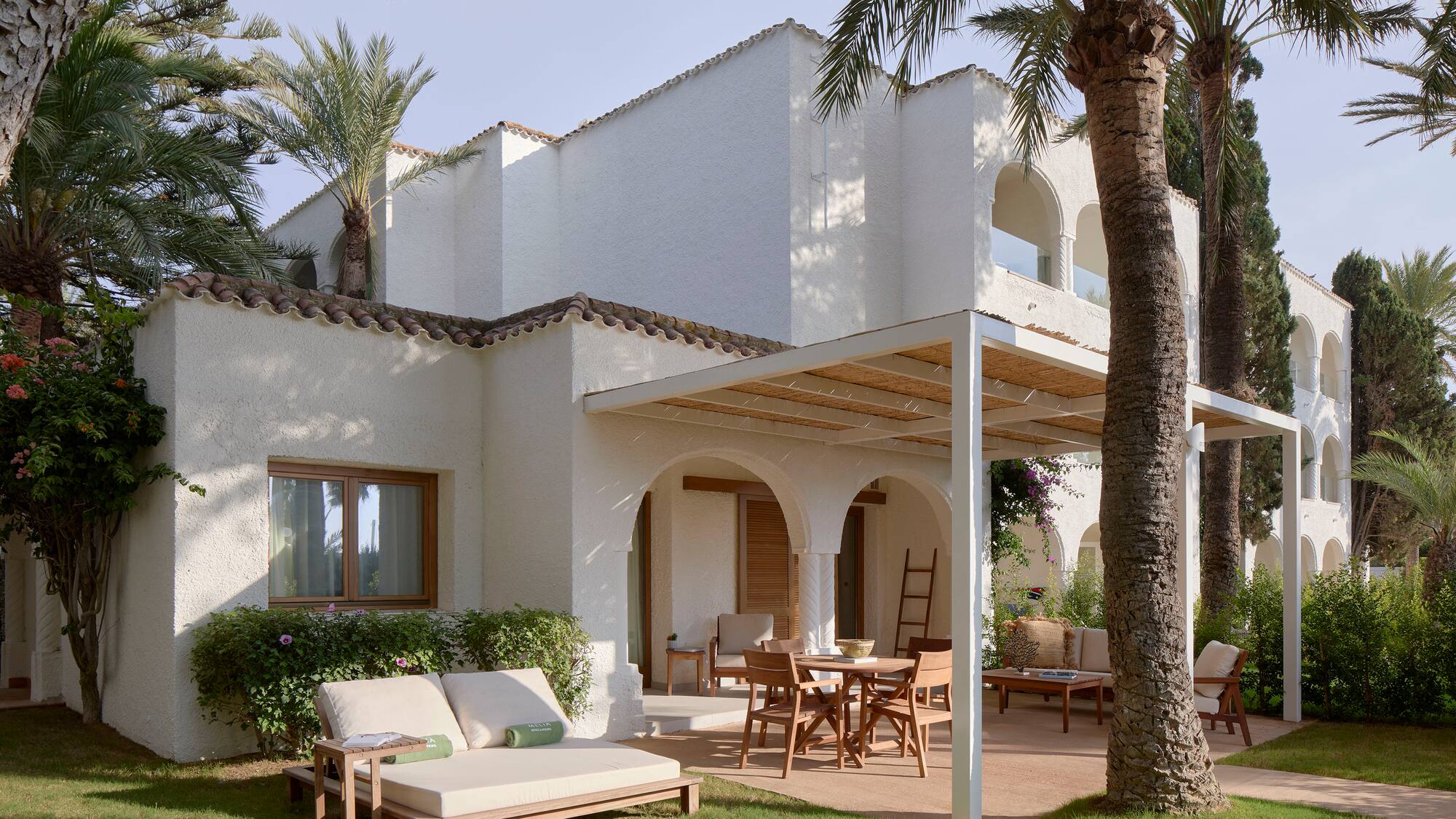 a patio area with chairs and tables in front of a white building