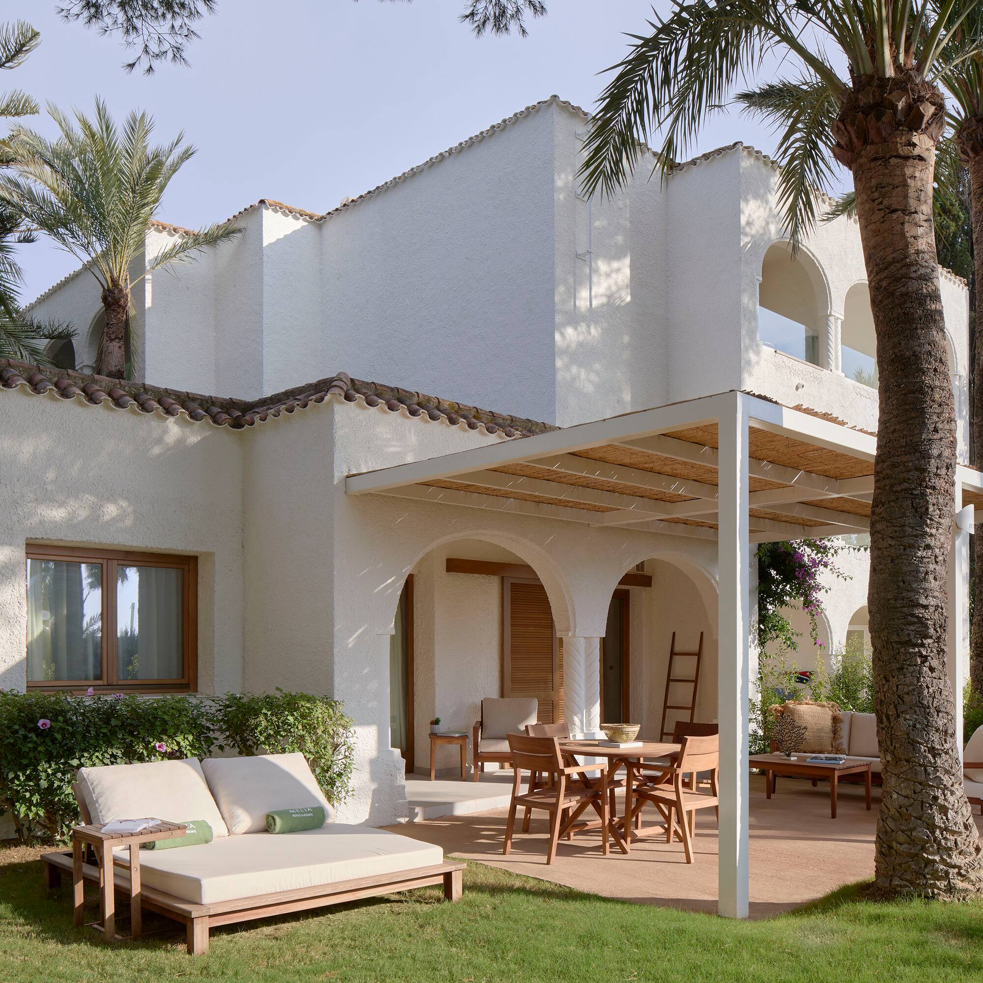 a patio area with chairs and tables in front of a white building