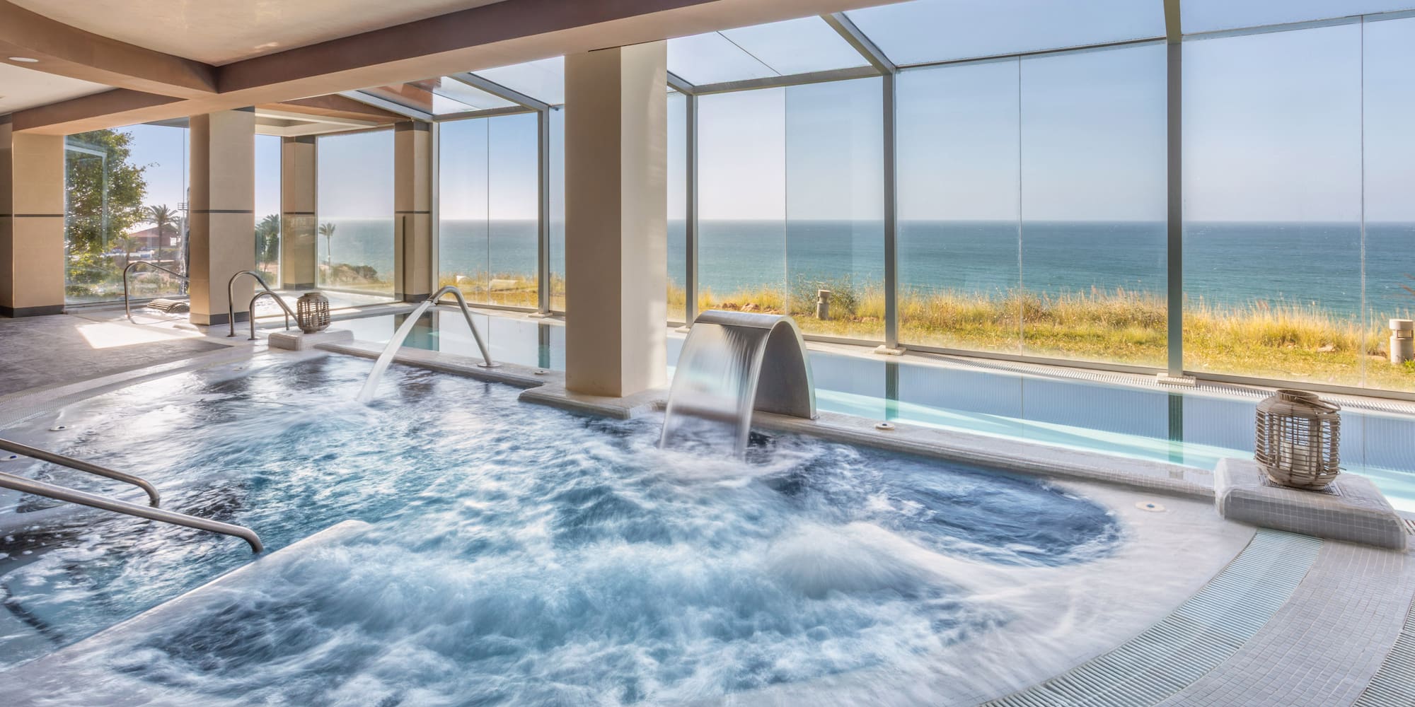 Indoor spa pool with bubbling jacuzzi, water features, and ocean view.