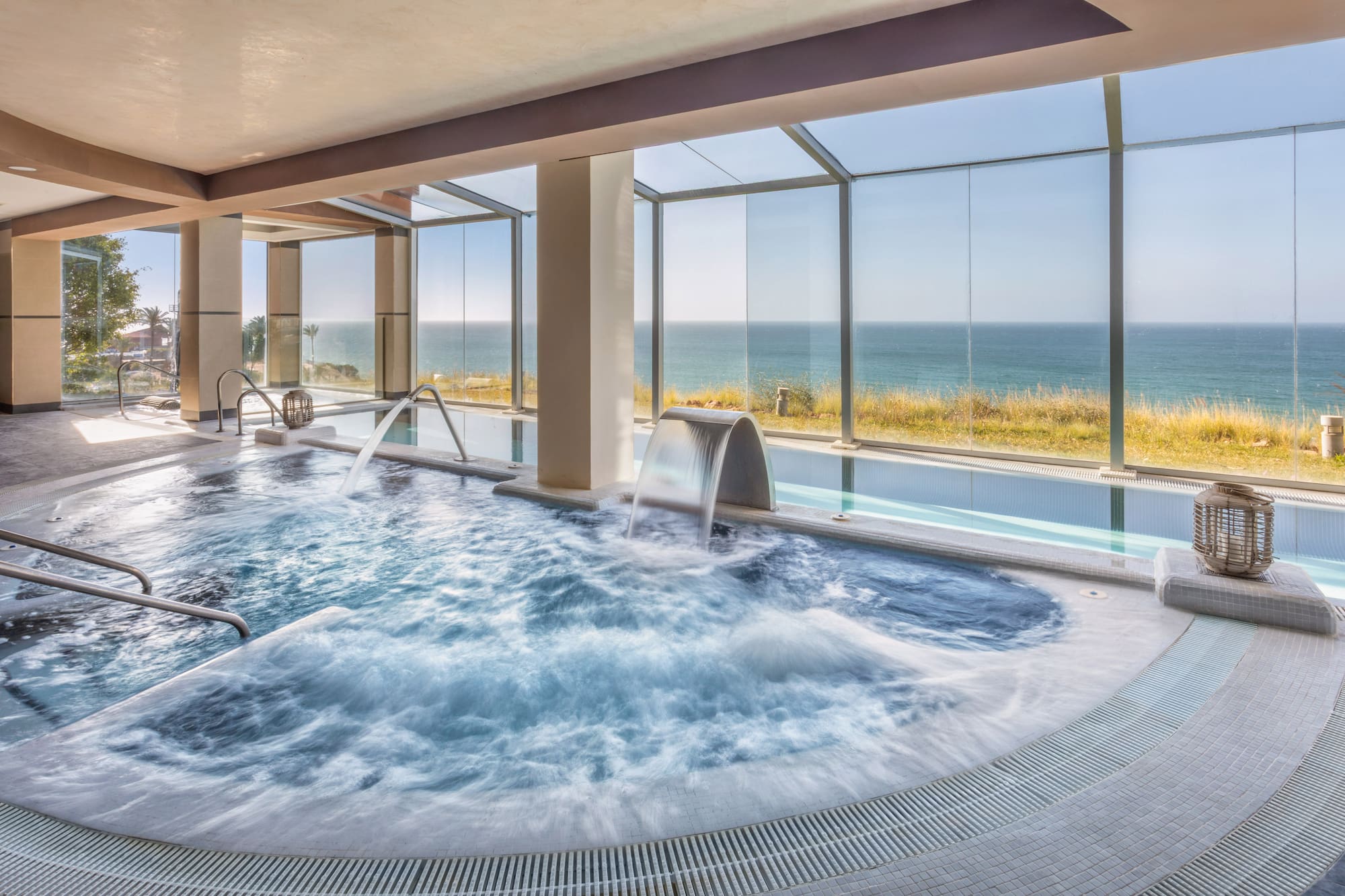 Indoor spa pool with bubbling jacuzzi, water features, and ocean view.