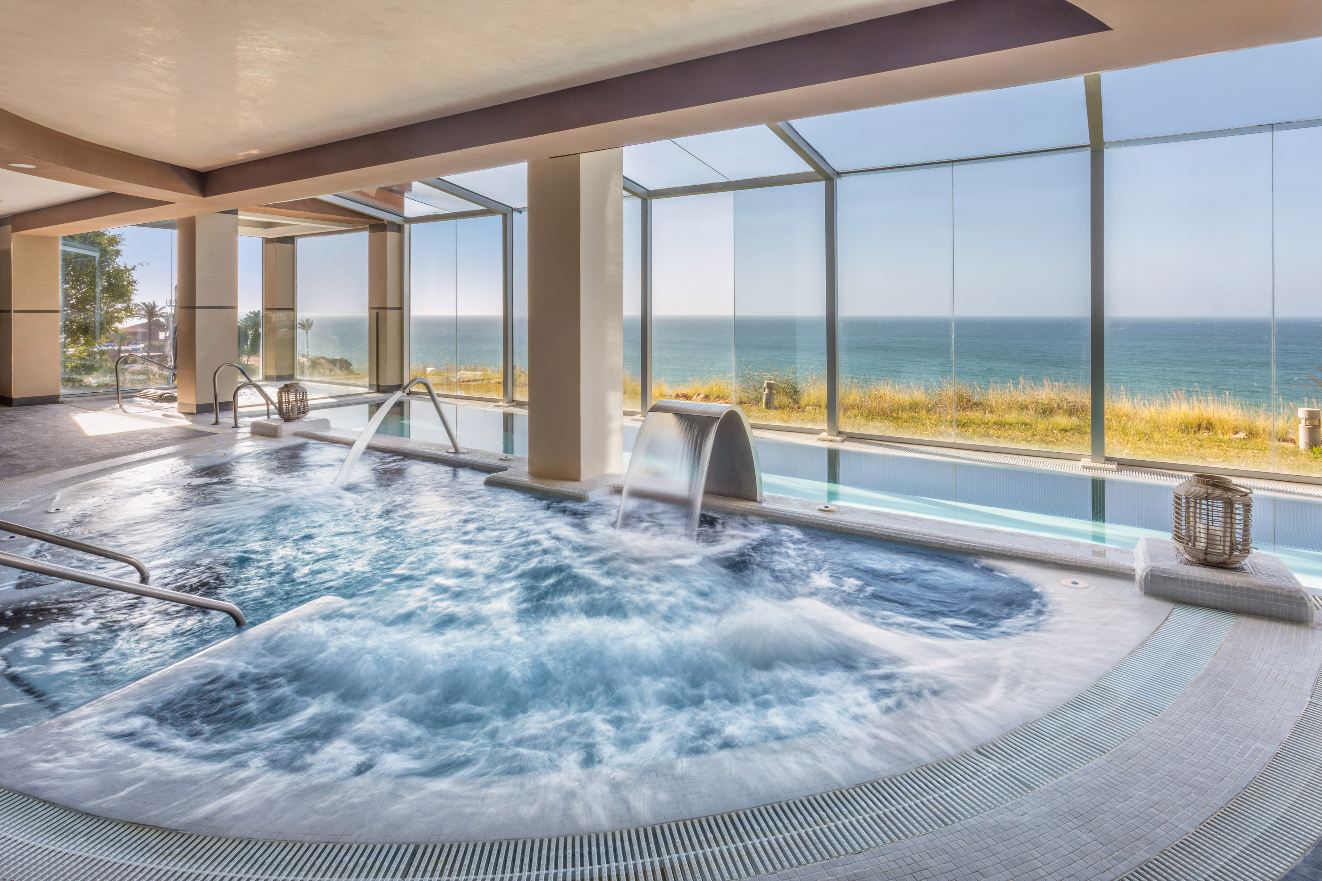 Indoor spa pool with bubbling jacuzzi, water features, and ocean view.