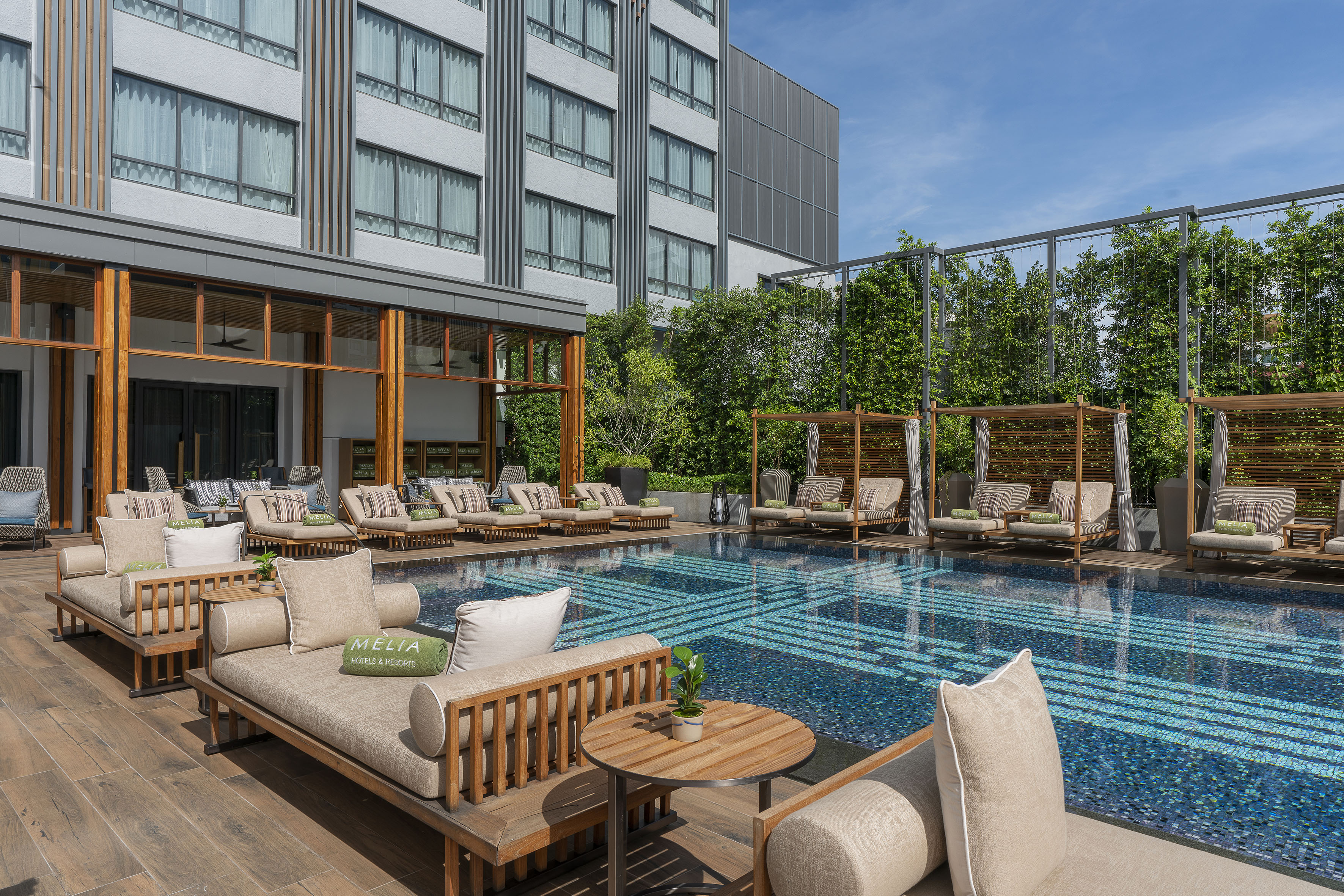 Meliá resort outdoor pool with daybeds, cabanas, and modern hotel building.