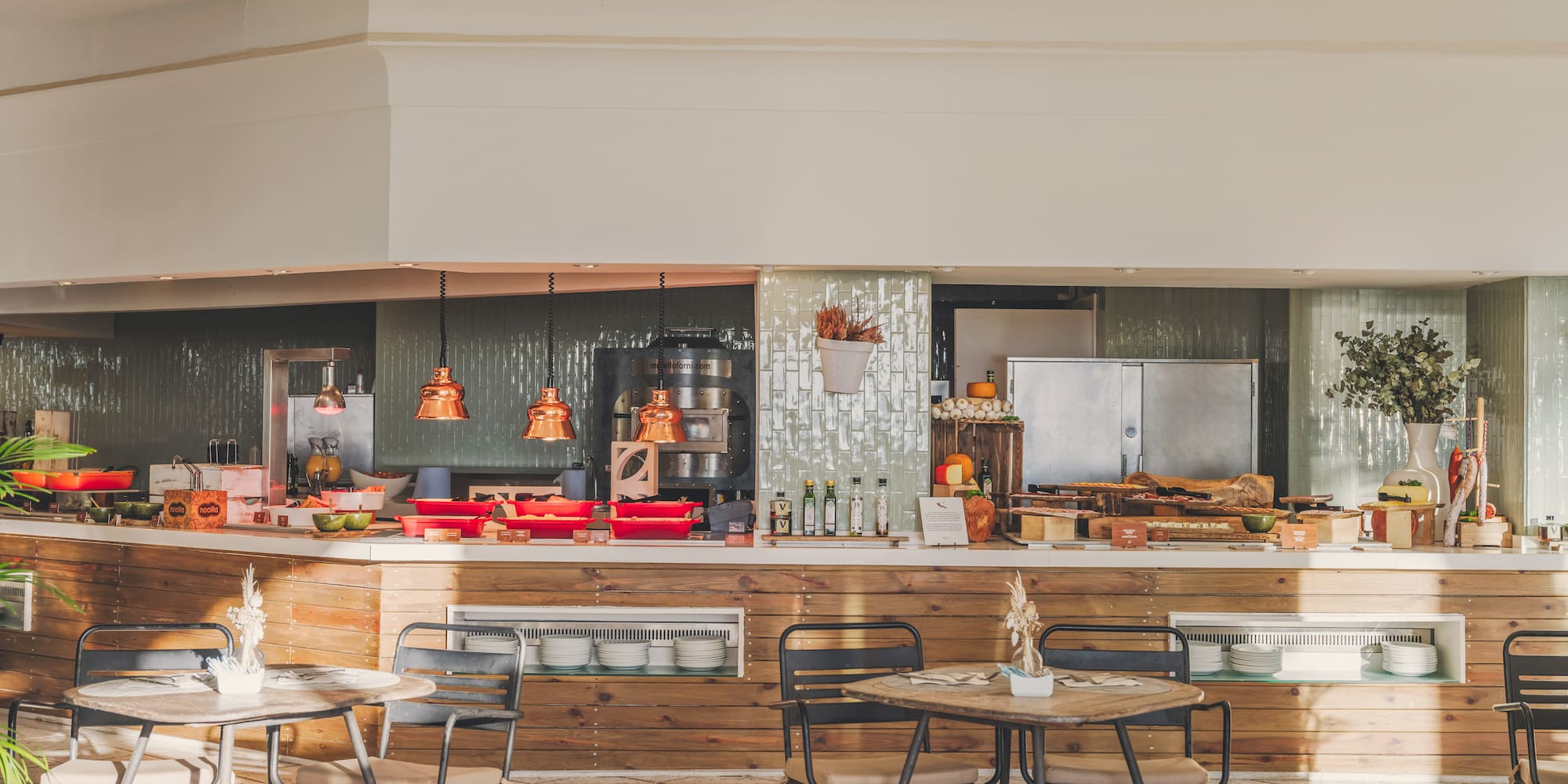 Bright buffet restaurant with food display, wooden counter, tables and chairs.