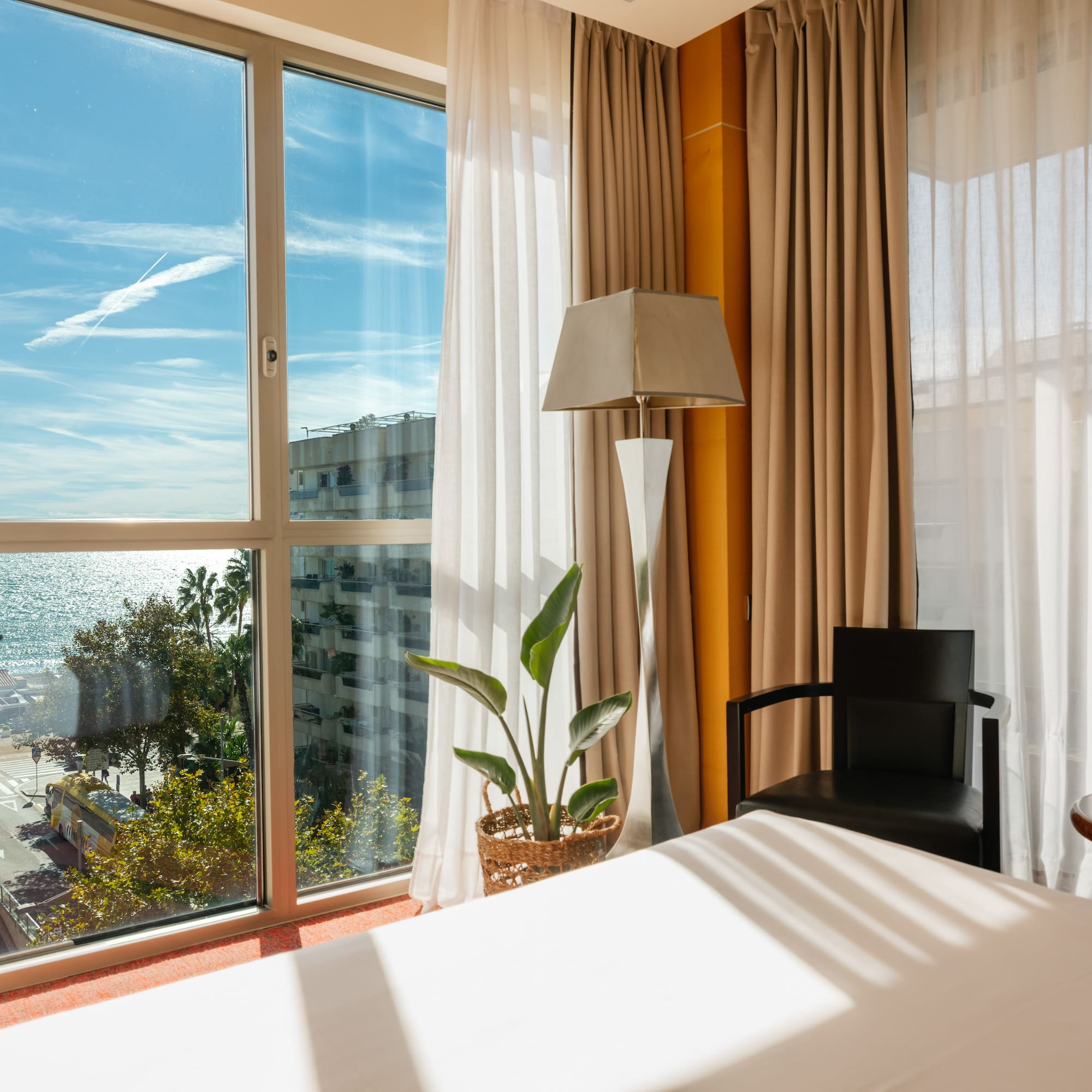 Habitación de hotel con ventanal, vista a la playa y al mar.