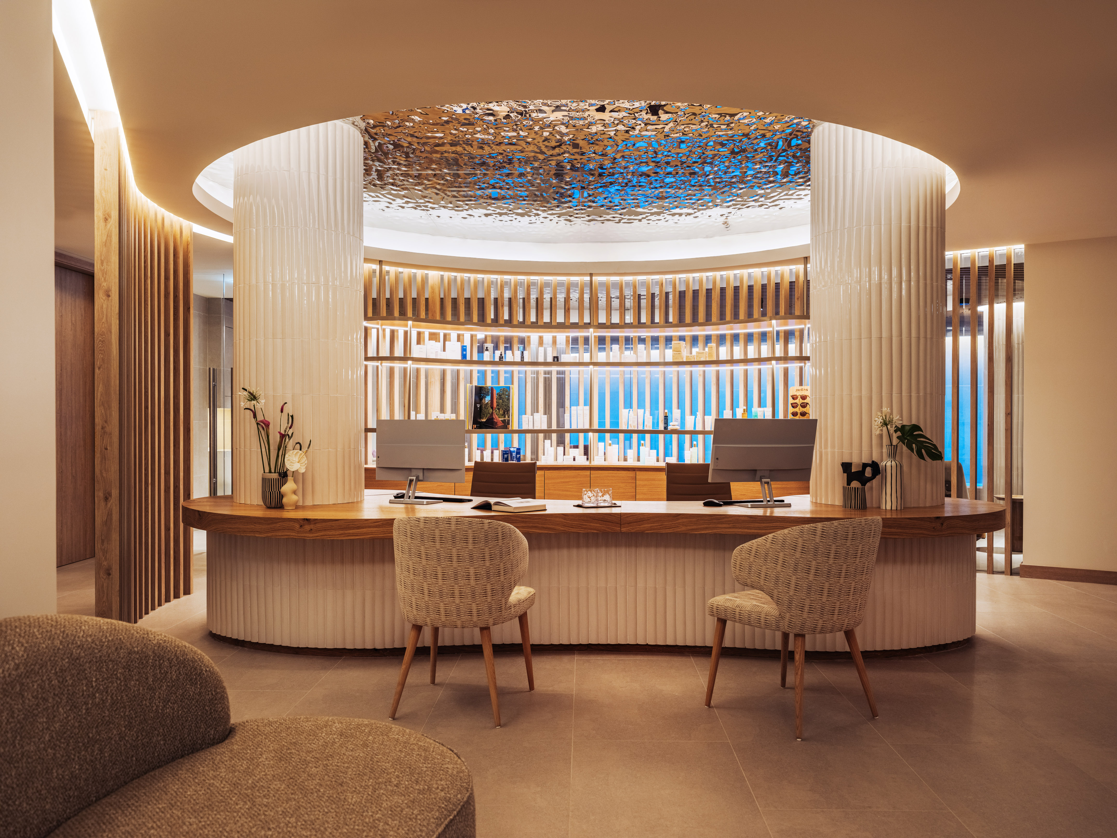 Elegant spa reception desk with circular counter, warm lighting, and product display.