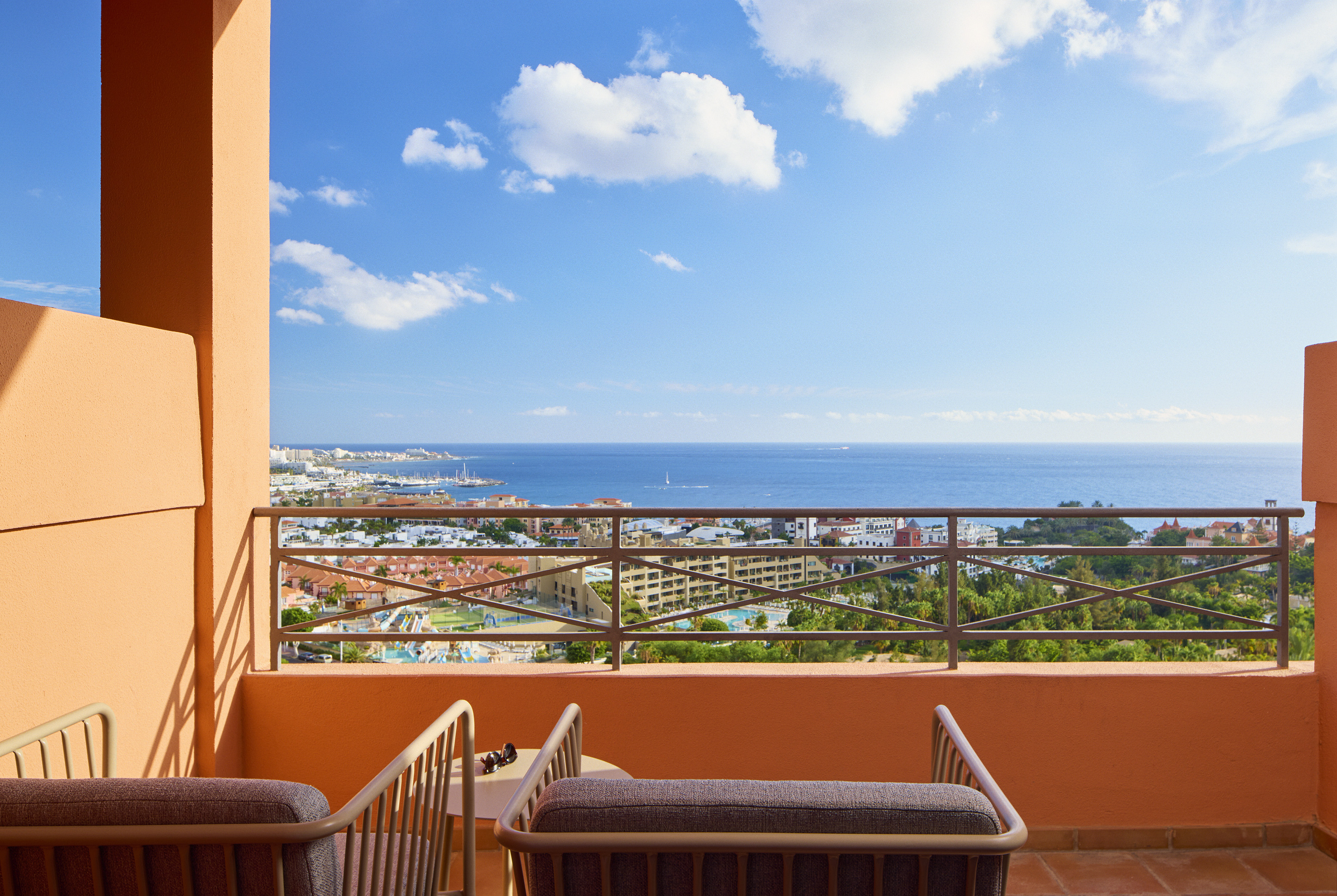 Hotel balcony with ocean view over coastal resort town and marina.
