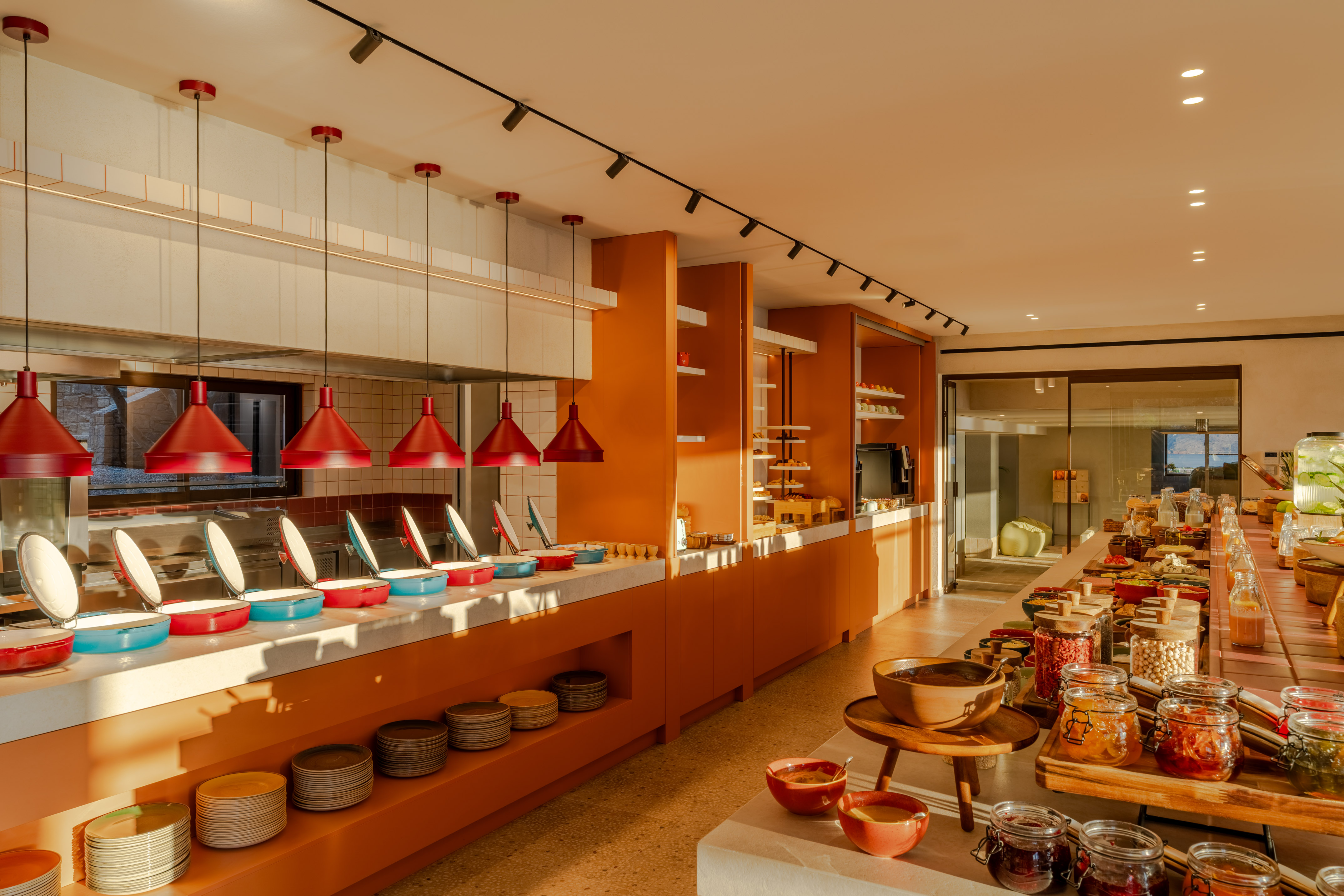 Bright modern buffet with orange decor, hot food station, and breakfast items.