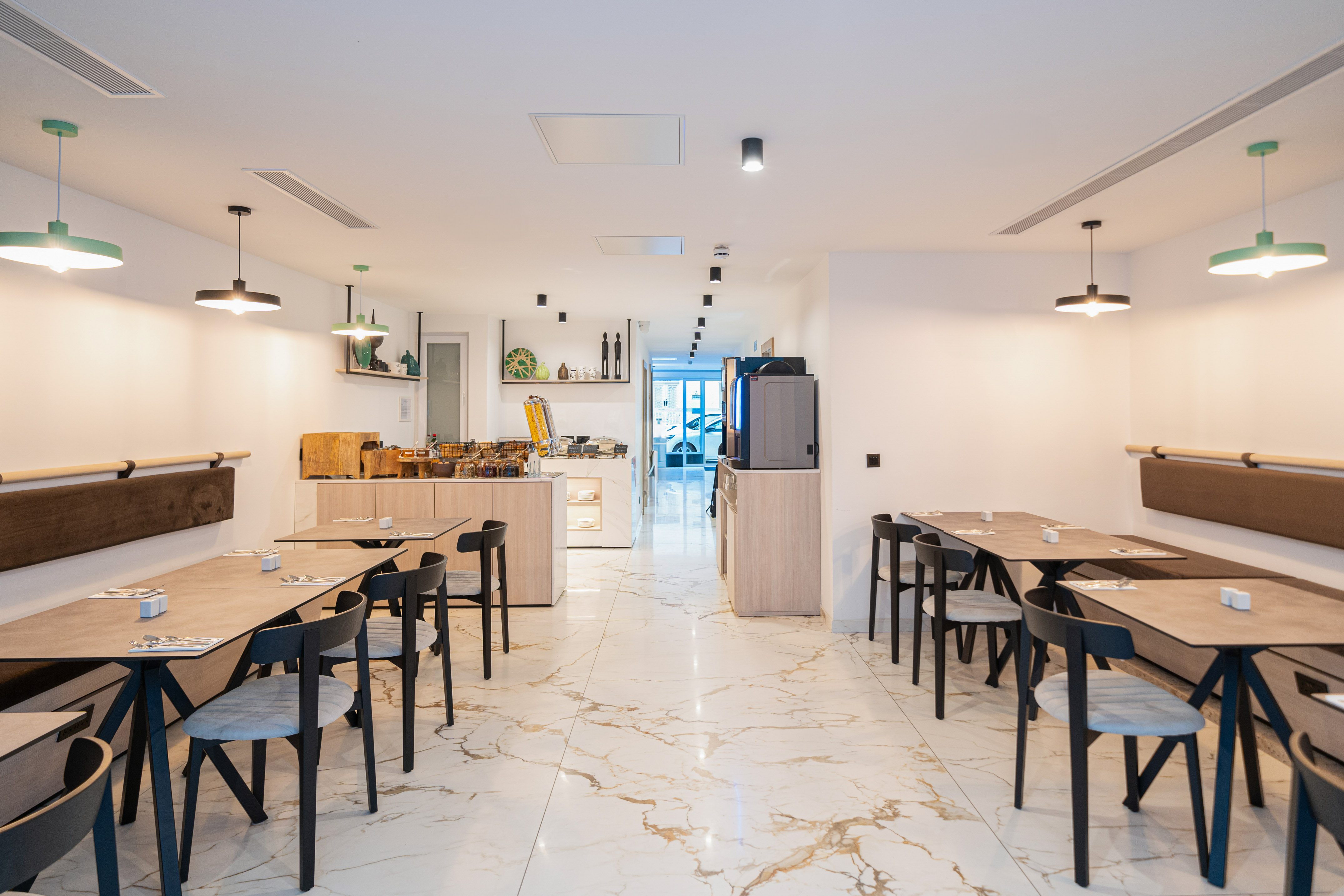 Modern dining room with buffet, wooden tables, black chairs, and marble floor.