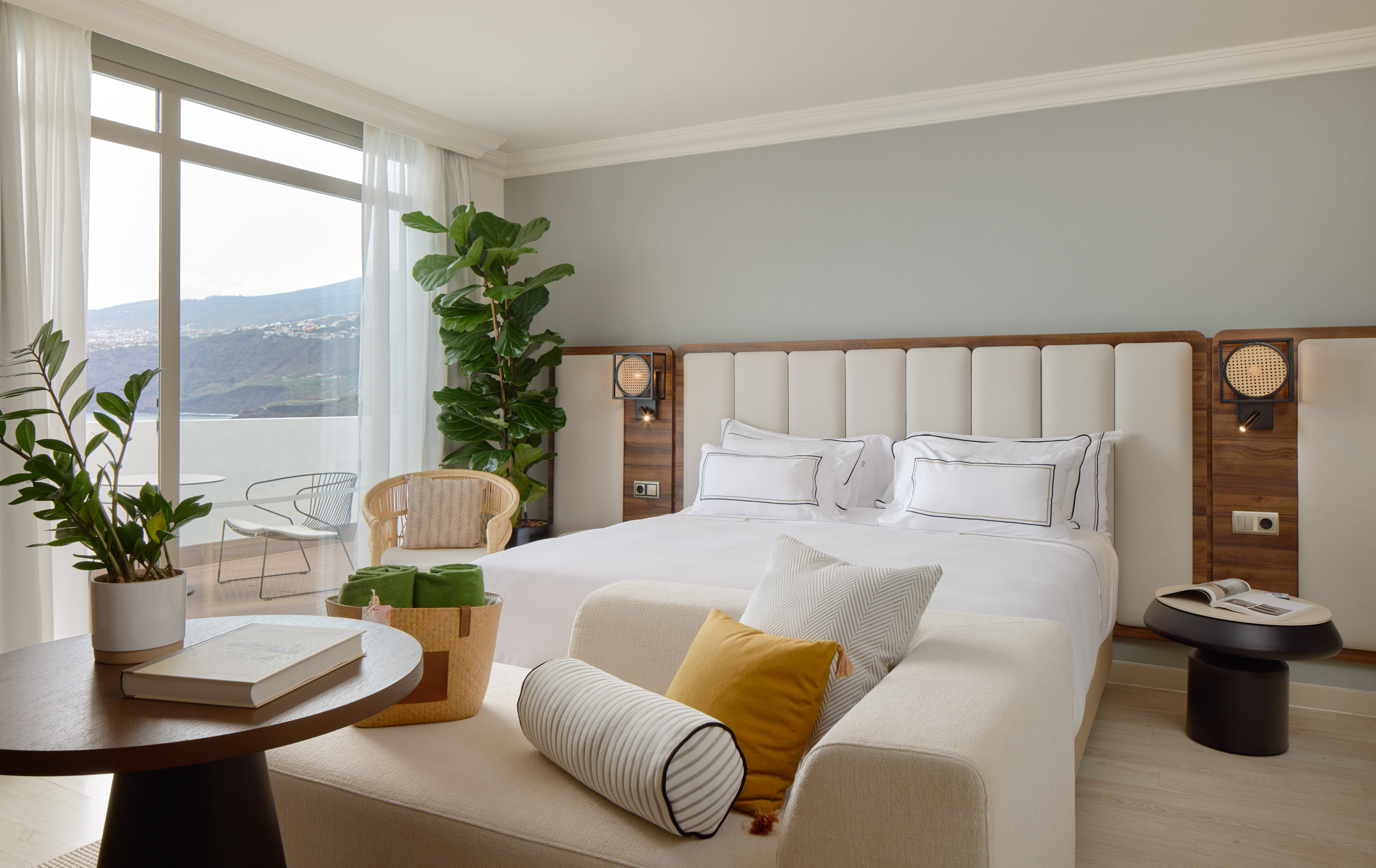 Modern hotel bedroom suite with king bed, balcony, and scenic mountain views.