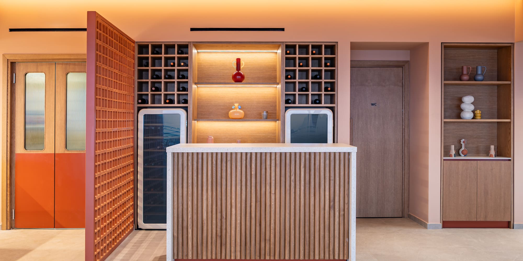 Stylish reception bar with wine shelves, wood paneling, and peach walls.
