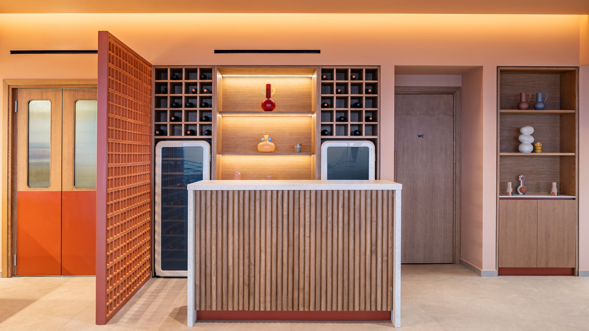 Stylish reception bar with wine shelves, wood paneling, and peach walls.