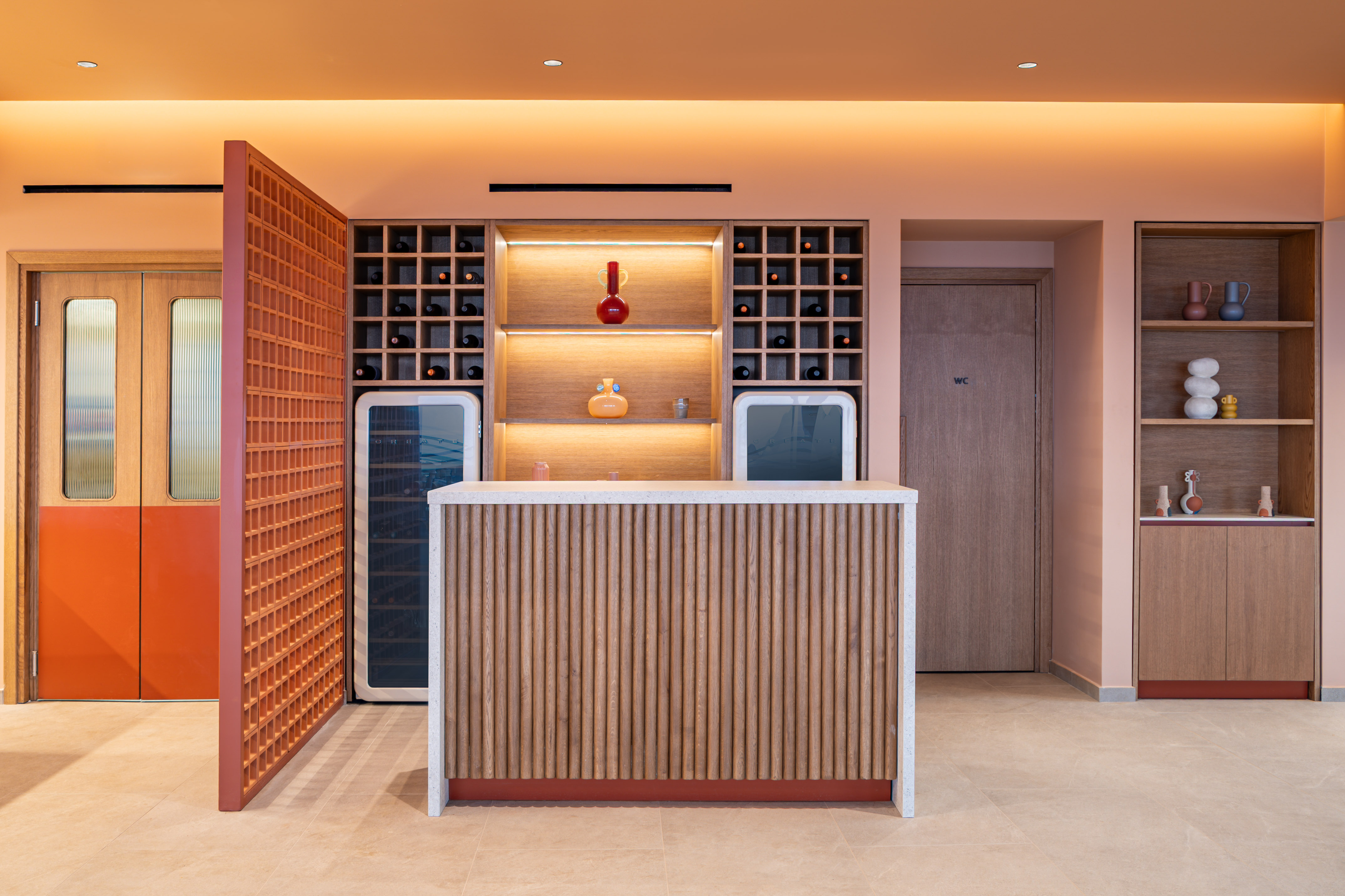 Stylish reception bar with wine shelves, wood paneling, and peach walls.