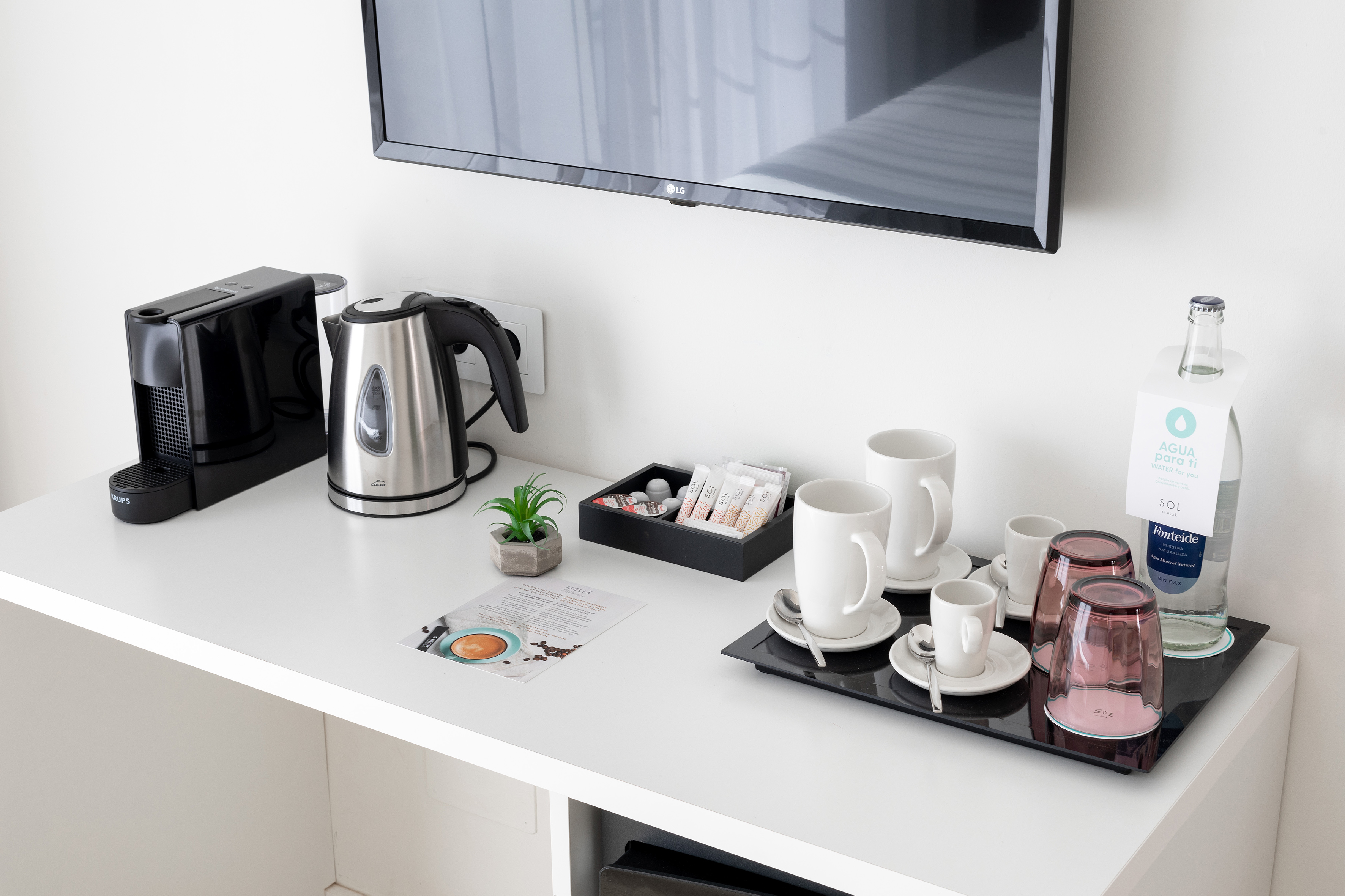 Hotel room amenities: Krups coffee machine, kettle, cups, bottled water, LG TV.