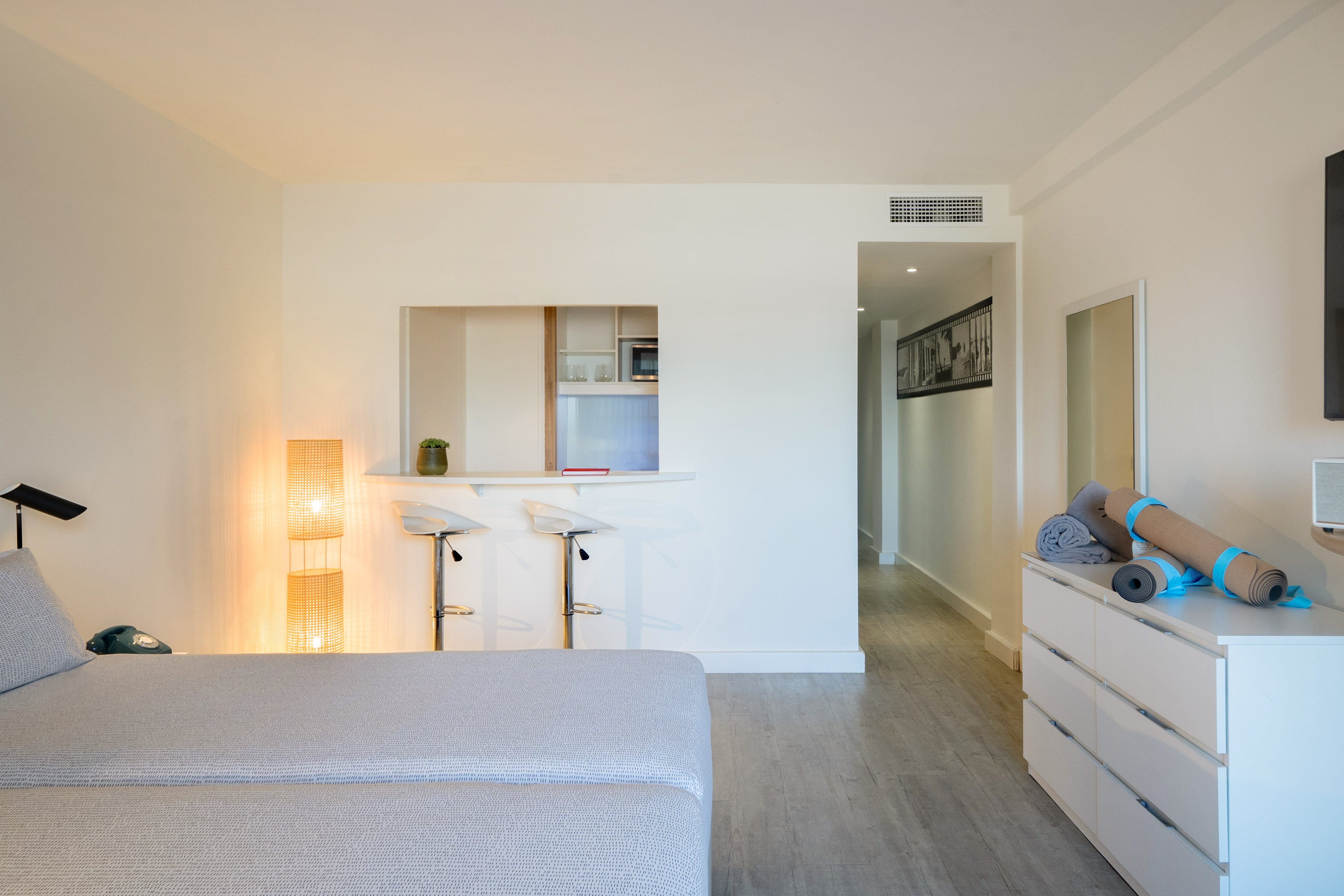 Modern studio apartment with kitchenette bar, stools, and yoga mats.