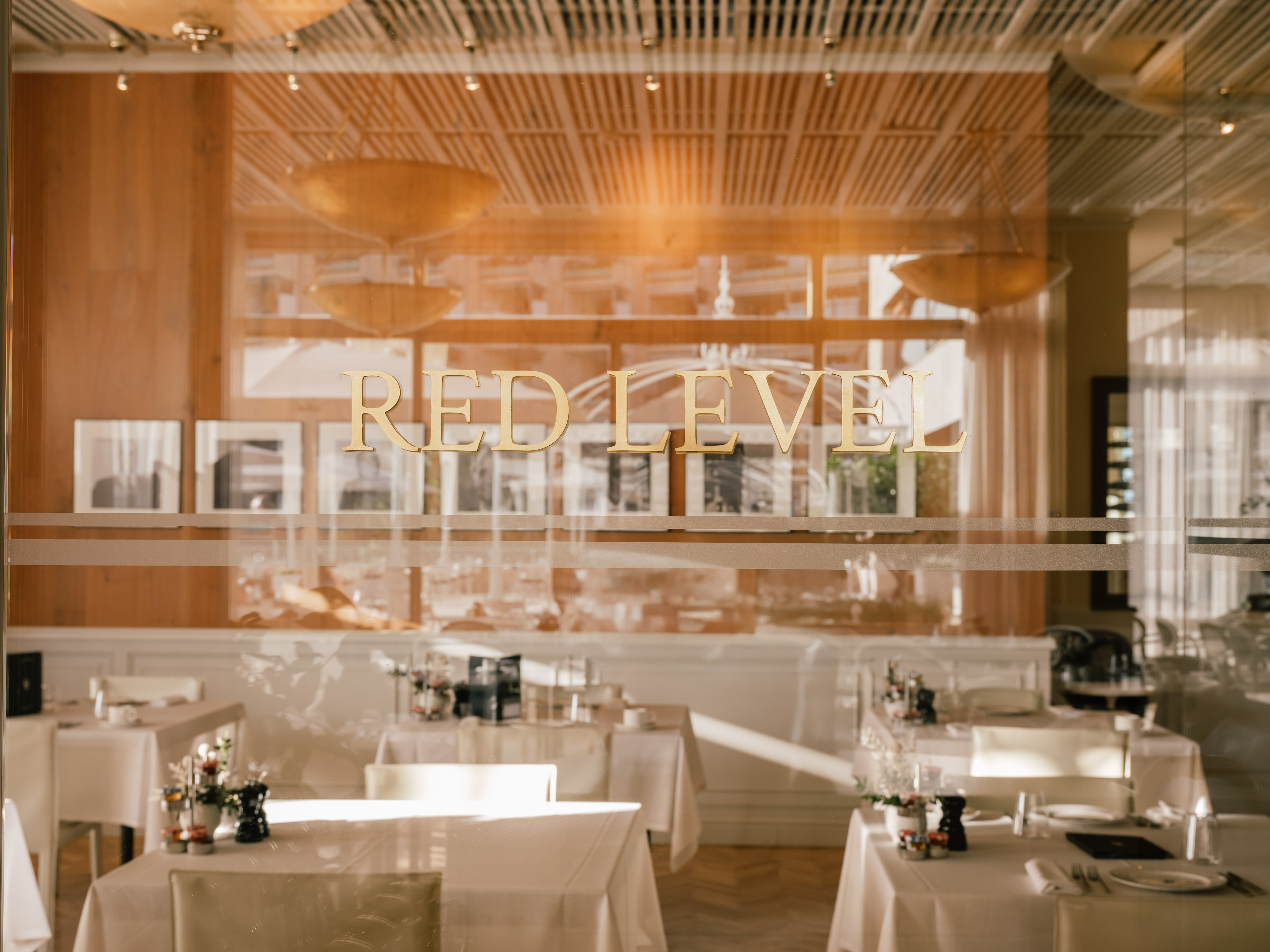 RED LEVEL sign on glass, showing an elegant restaurant interior with dining tables.