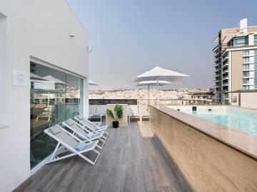 a pool with chairs and umbrellas on a rooftop