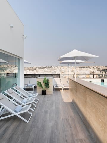 a pool with chairs and umbrellas on a rooftop