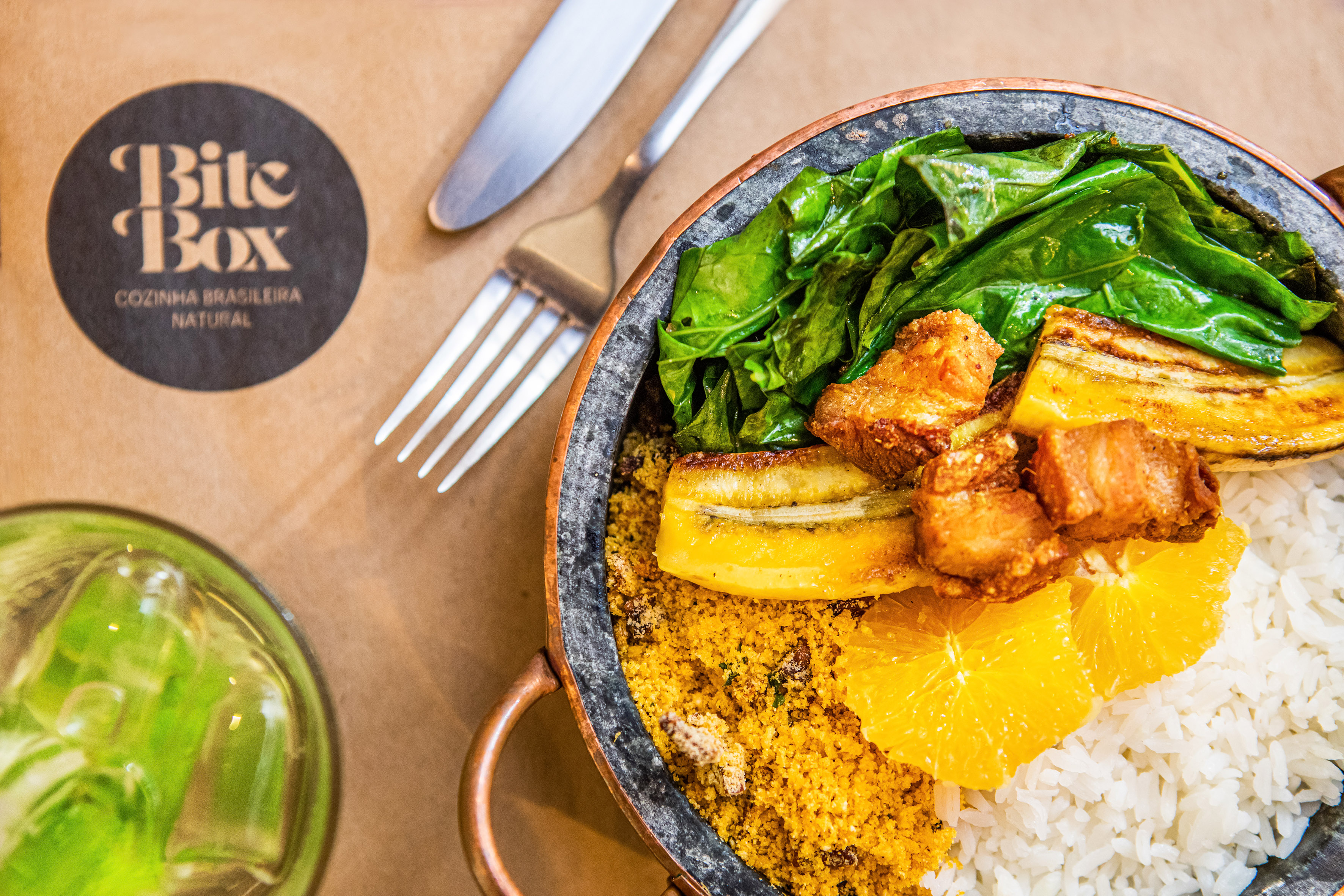 Brazilian dish with rice, greens, pork belly, plantains, farofa, and orange.