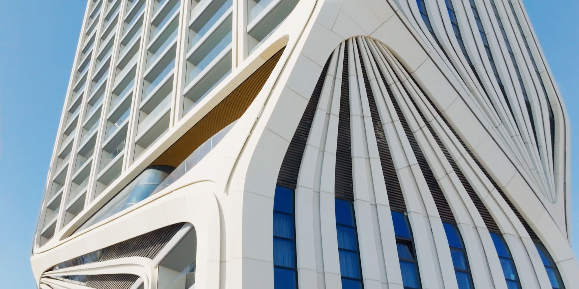 Sleek, white curved facade of a modern skyscraper with blue windows.