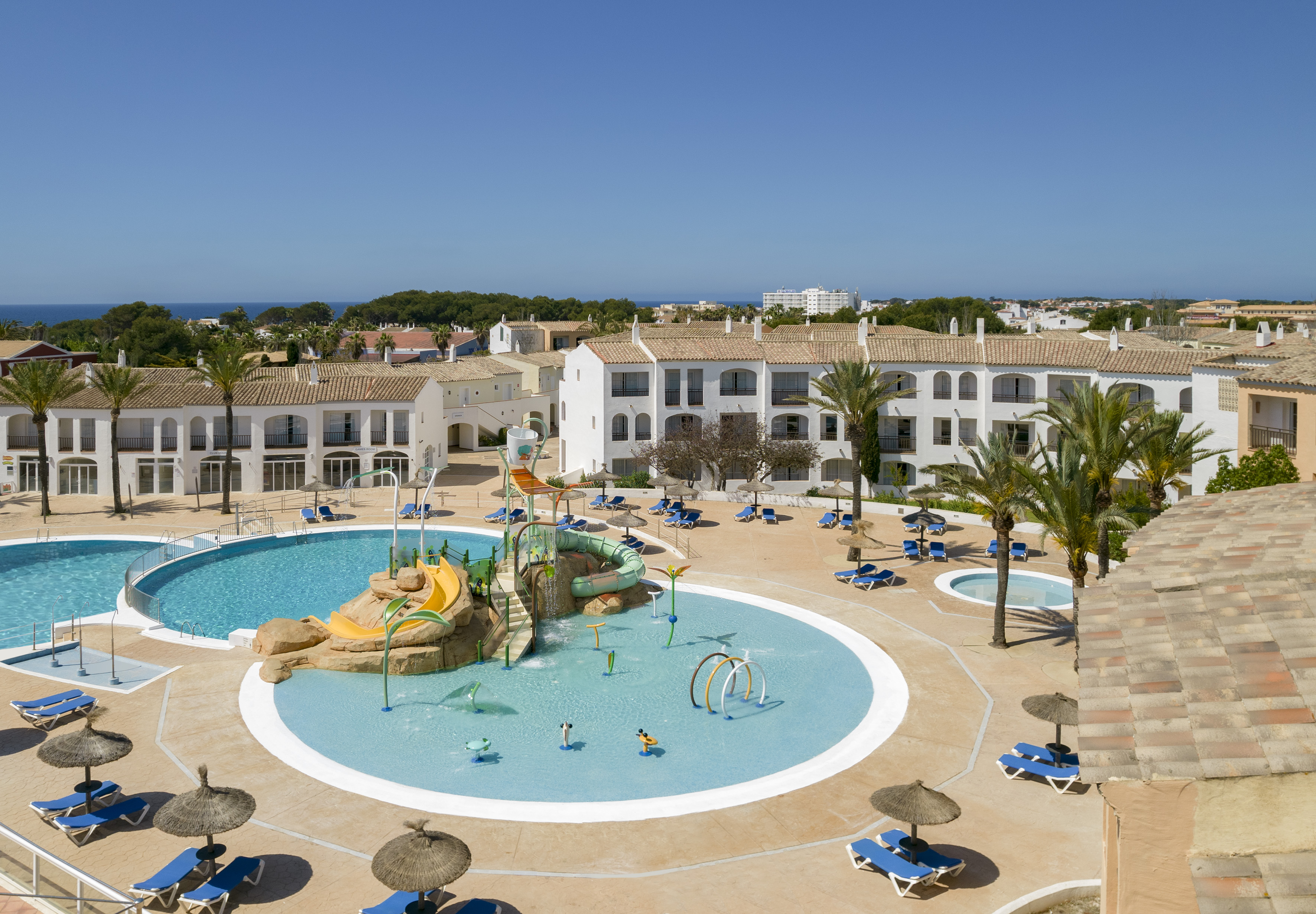Coastal resort: large pools, kids' water park with slides, and hotel buildings.