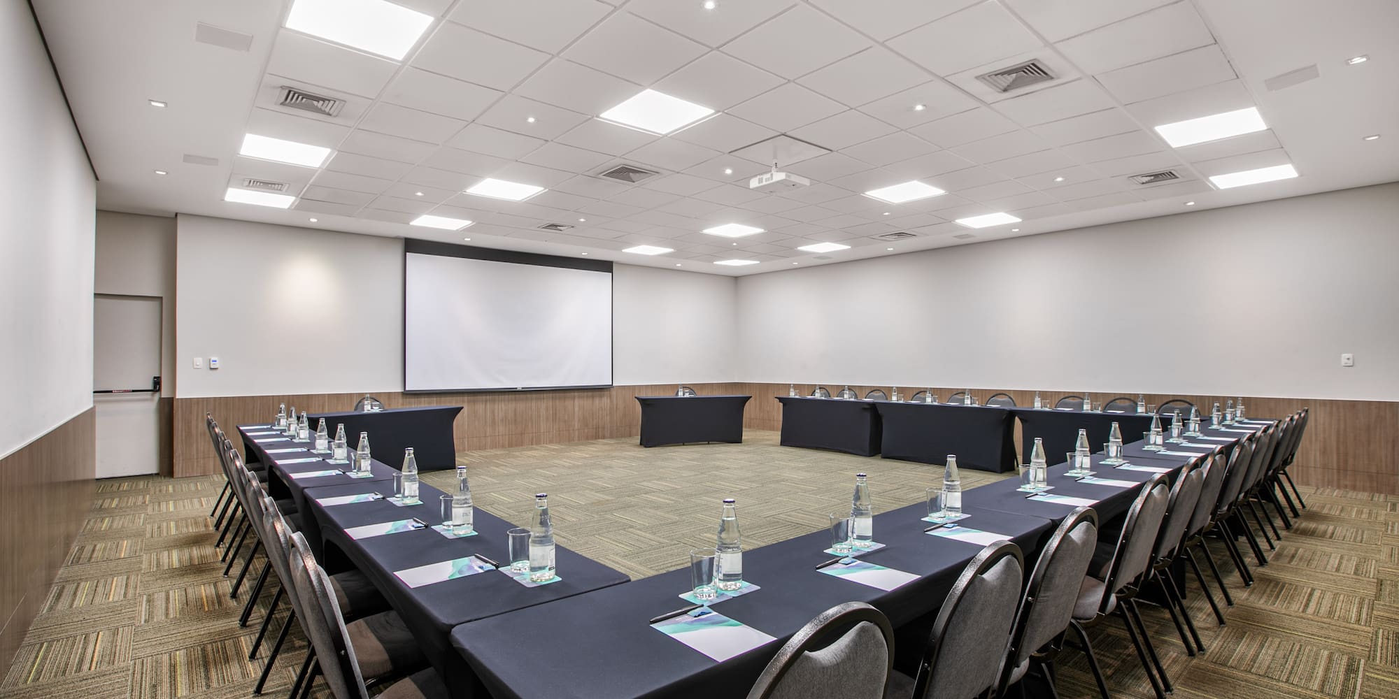 a room with a large table with chairs and a projector screen