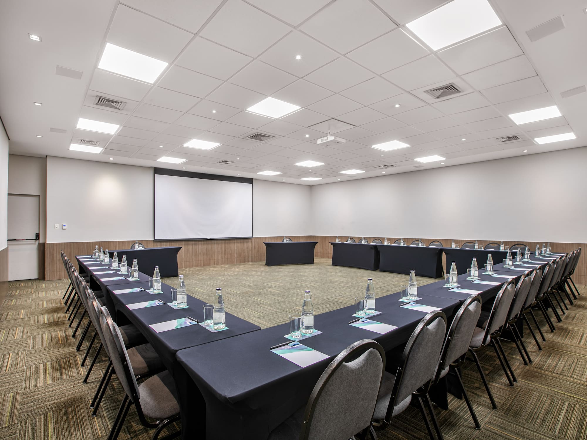 a room with a large table with chairs and a projector screen