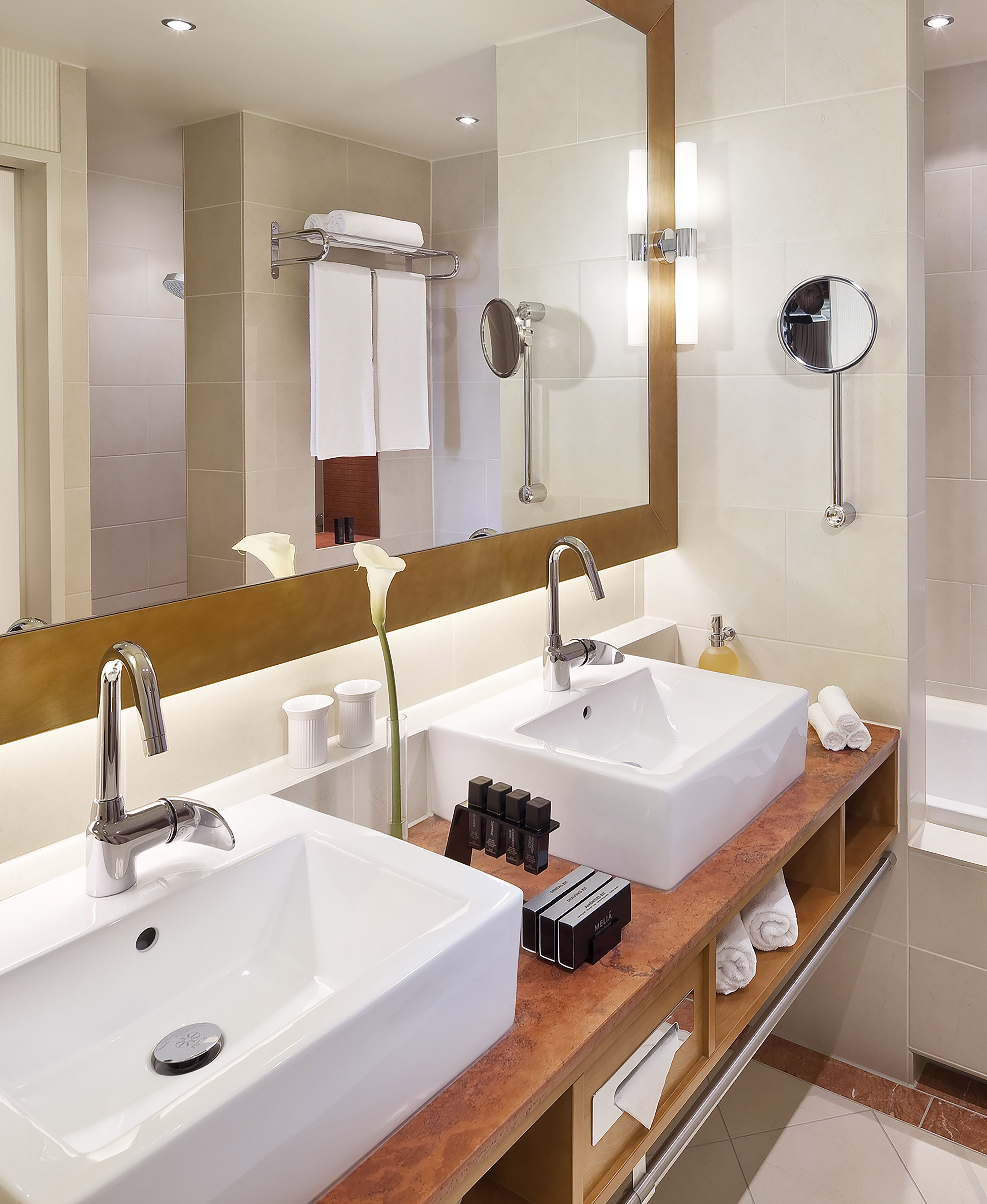 Modern hotel bathroom with double vanity, white sinks, chrome faucets, and toiletries. - The Level Grand Suite - Meliá Berlin, Berlín