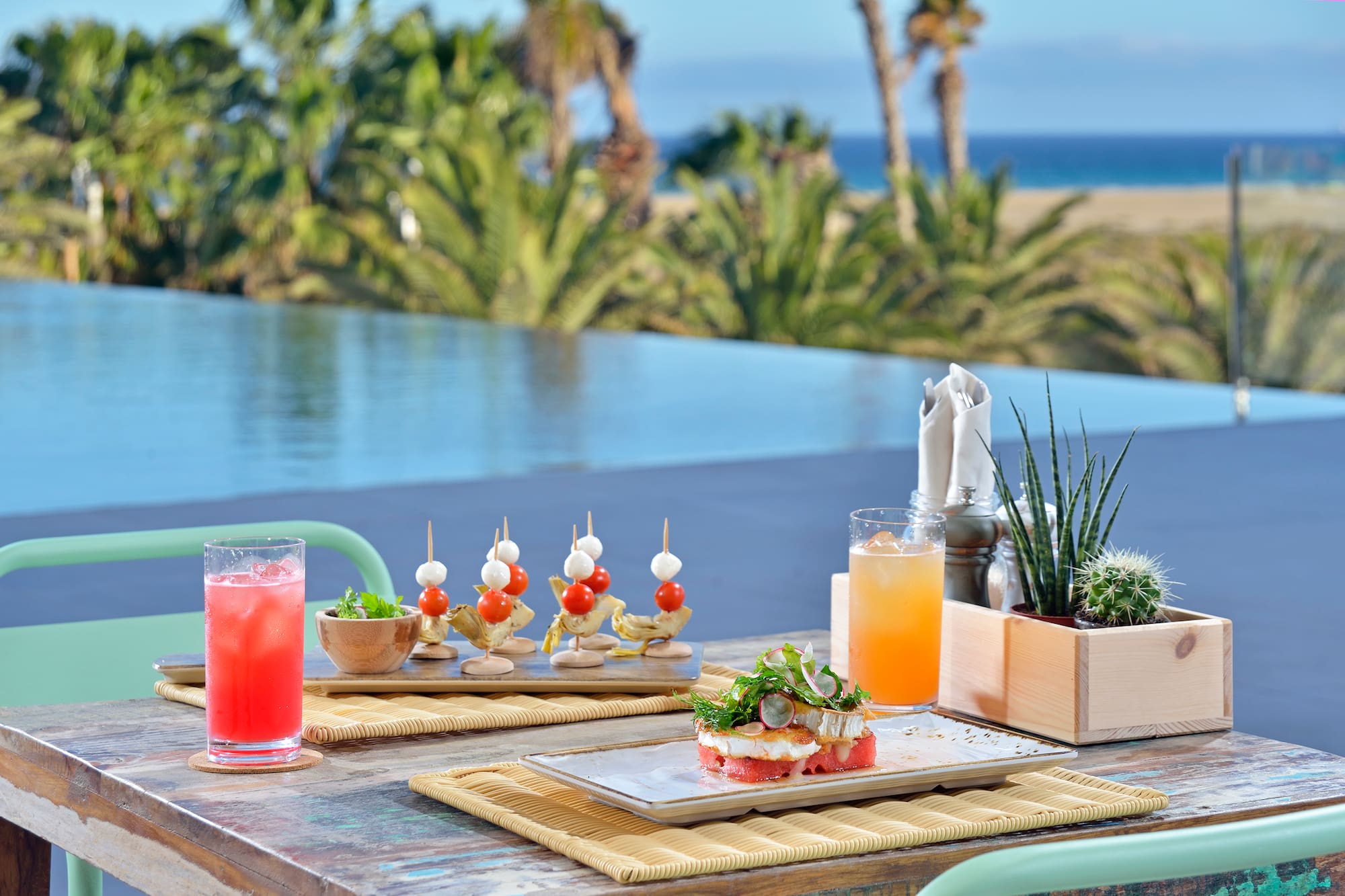 Tropical dining with cocktails and appetizers by infinity pool, ocean view.