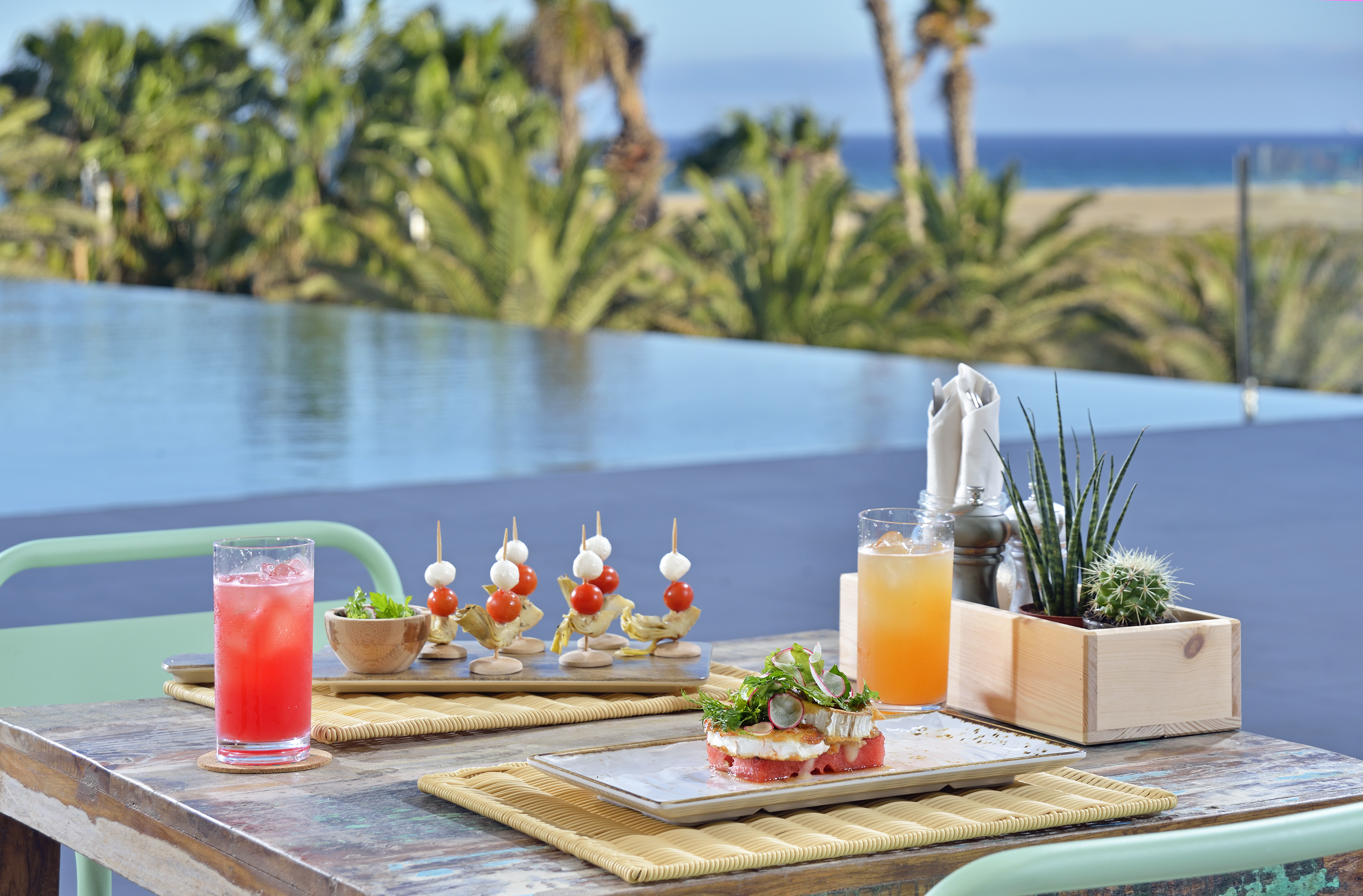 Tropical dining with cocktails and appetizers by infinity pool, ocean view.