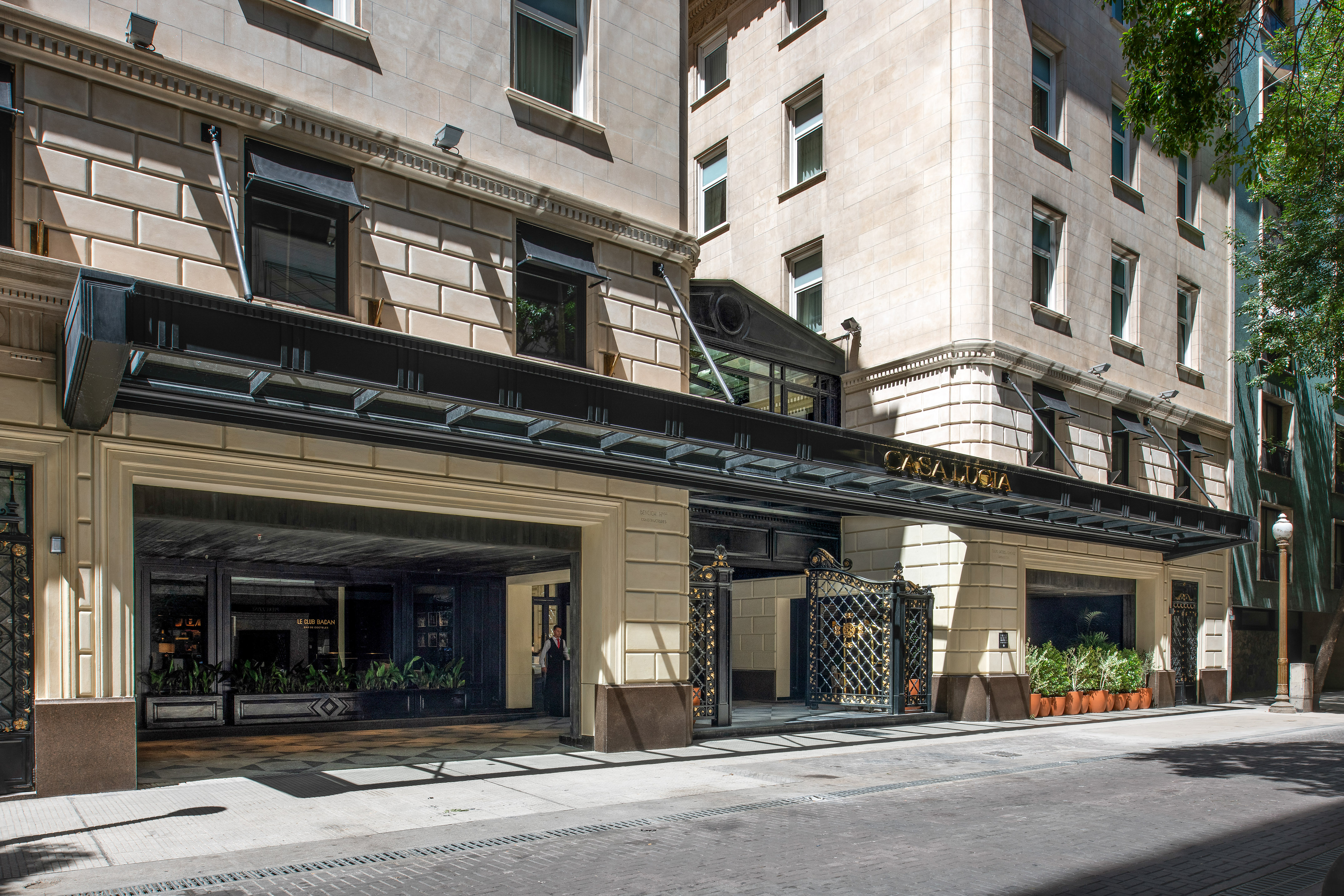 Urban stone building facade with white windows and black awnings.