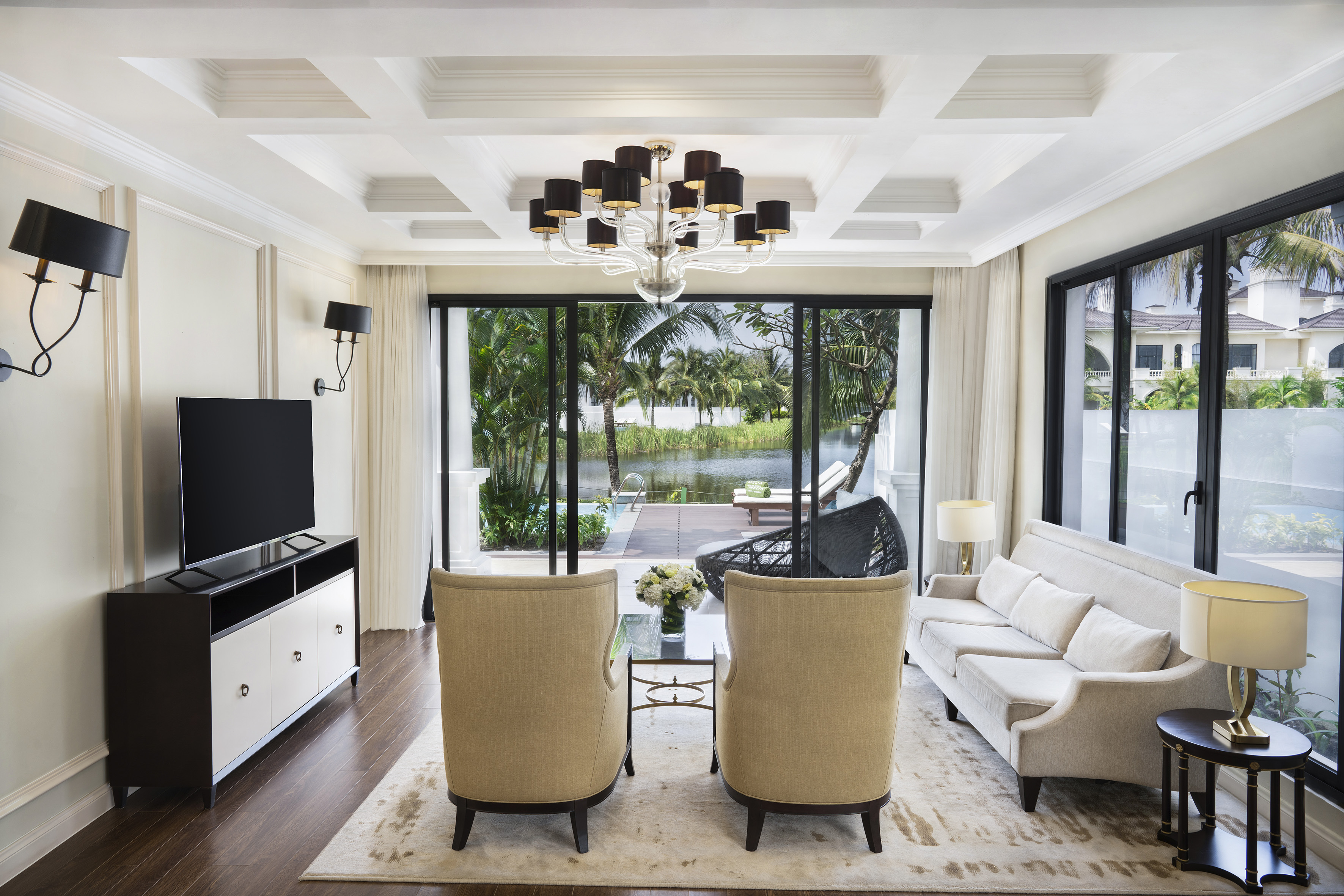 Luxurious living room with modern interior design and tropical waterfront view.